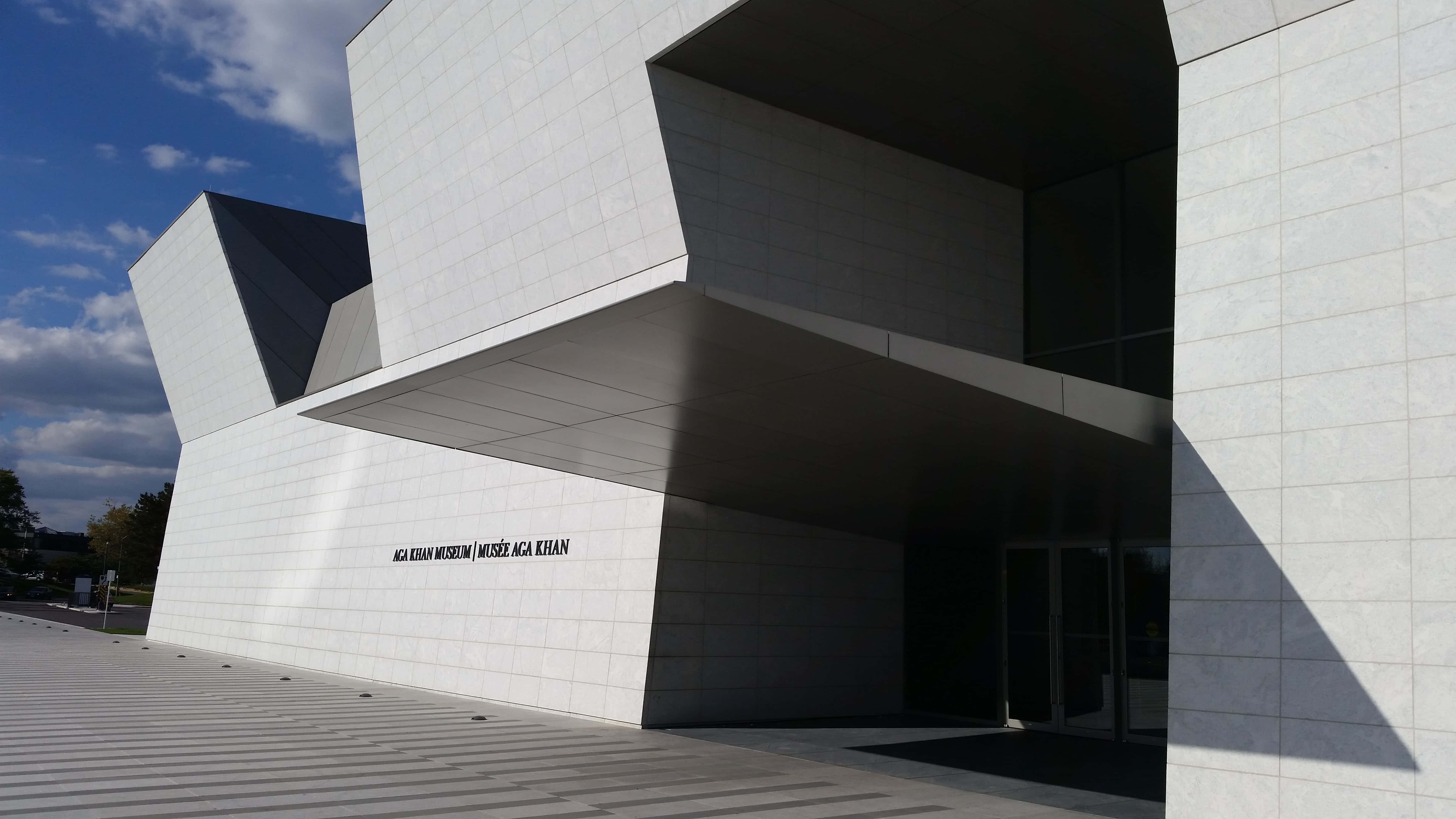 Aga Khan Museum 桌布 壁紙 — 現代白色幾何博物館建築，具有銳利角度和強烈陰影，部分多雲的藍天下。