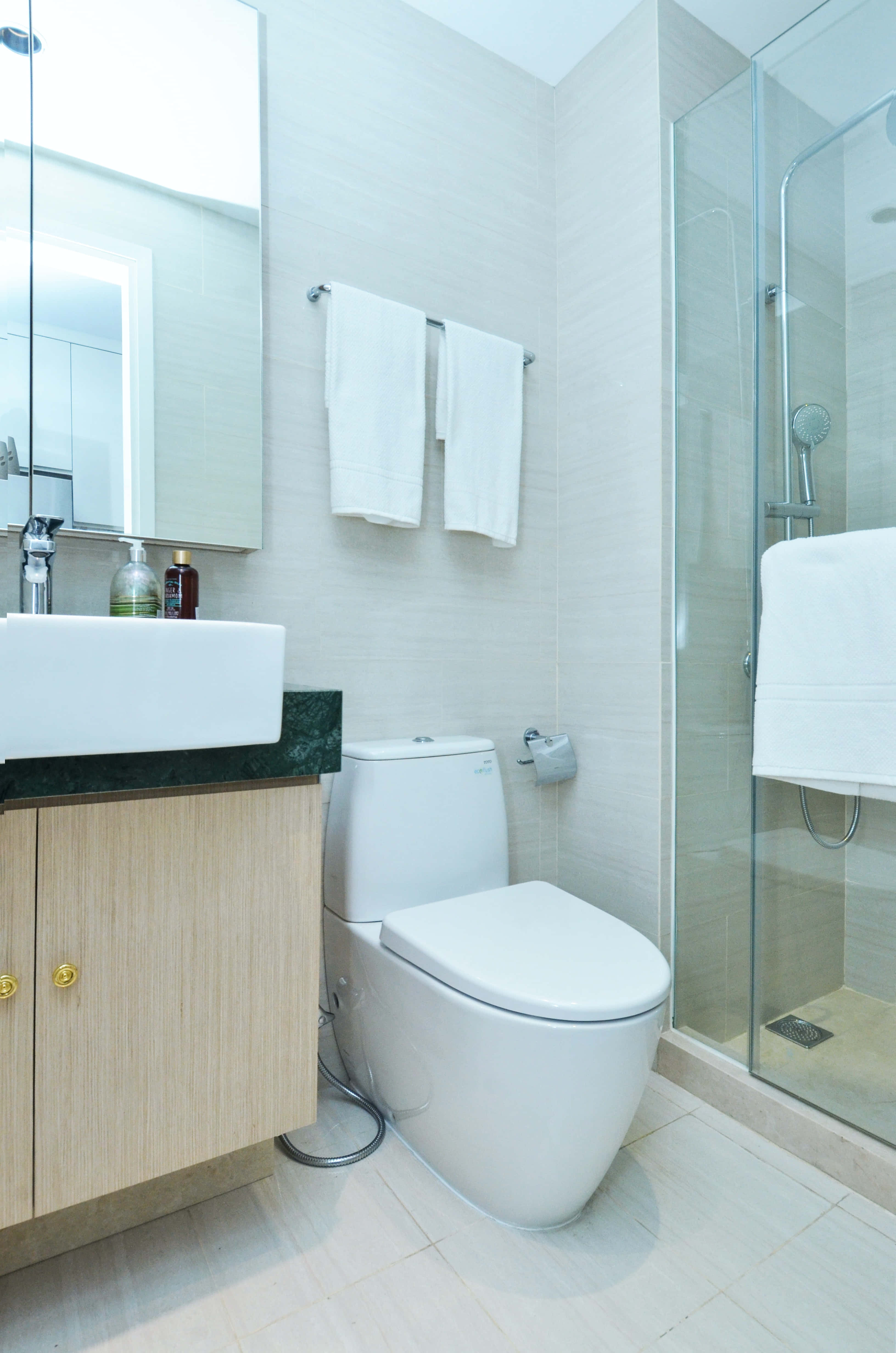 Toilet 桌布 壁紙 — 現代簡約浴室，配備白色潔具、淺色木質洗手台和玻璃淋浴間。
