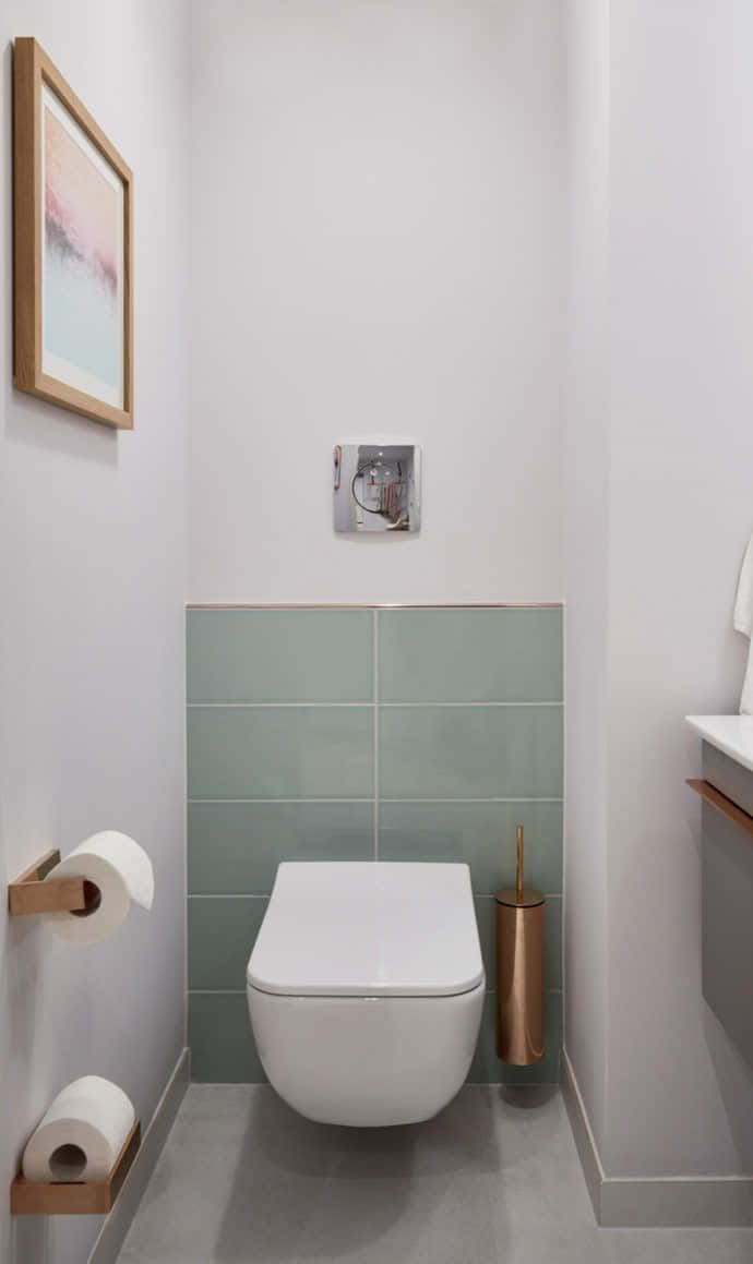 Toilet 桌布 壁紙 — 現代簡約浴室，配有掛牆馬桶、薄荷綠色瓷磚和銅色點綴，柔和環境燈光。