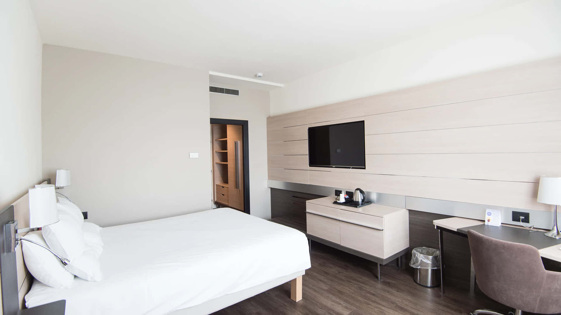Hotel Room 桌布 壁紙 — 現代簡約酒店客房，配備白色床鋪、木地板和時尚家具，光線充足。
