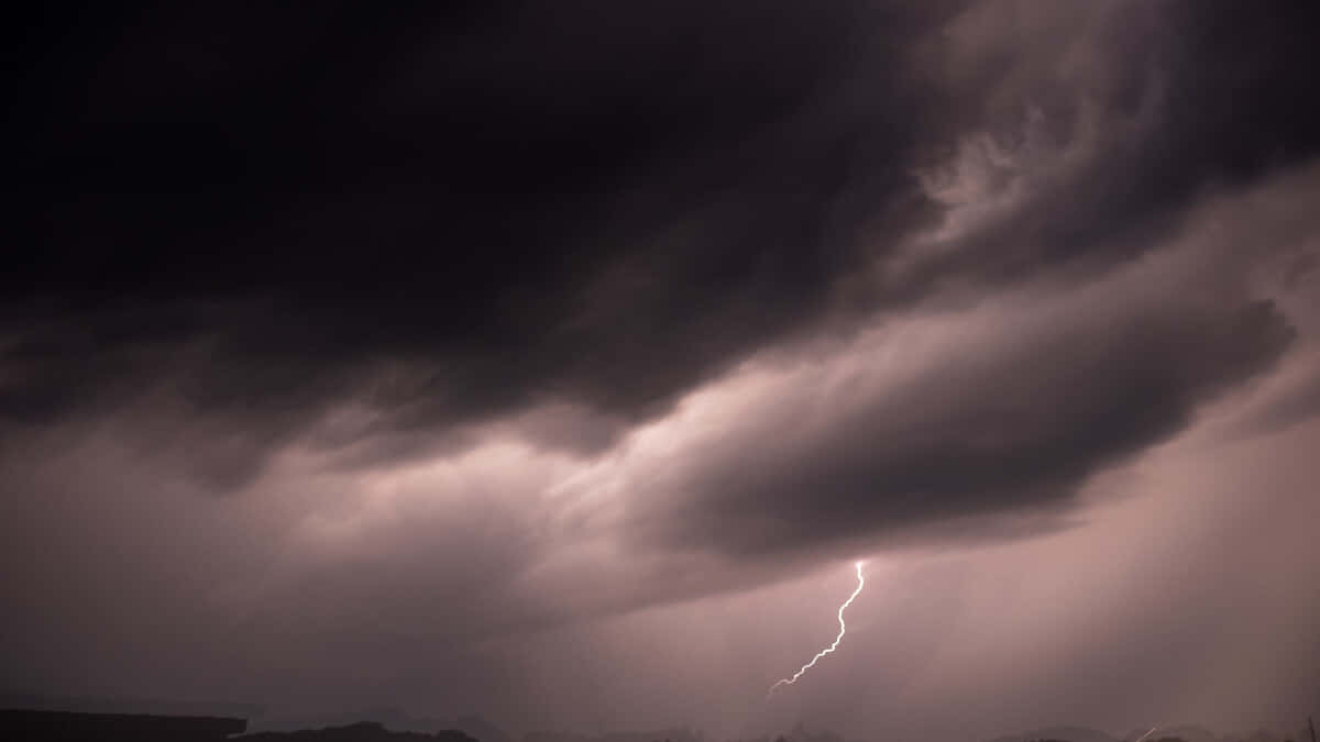 一道明亮的閃電穿過遠方風景上空黑暗的暴風雲層。