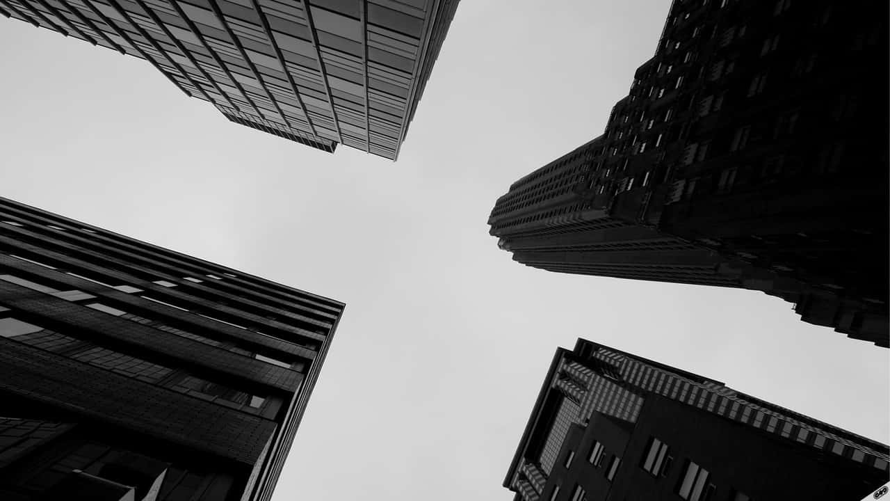 在高聳建築物之間向上看的黑白視角。
