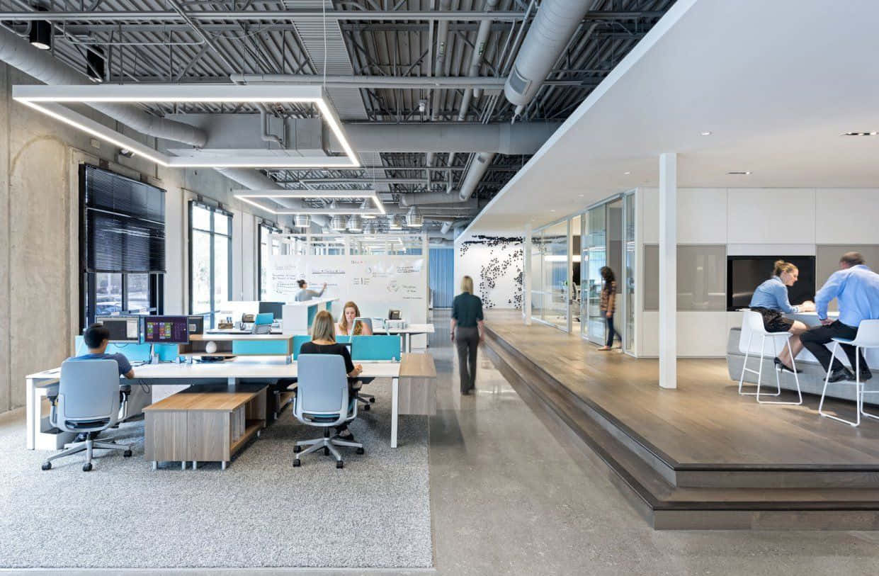 HD Office Background Minimalist Interior Design 壁紙 — 現代開放式辦公室，員工在辦公桌前工作，並設有高架休息區，下方為裸露的工業天花板。