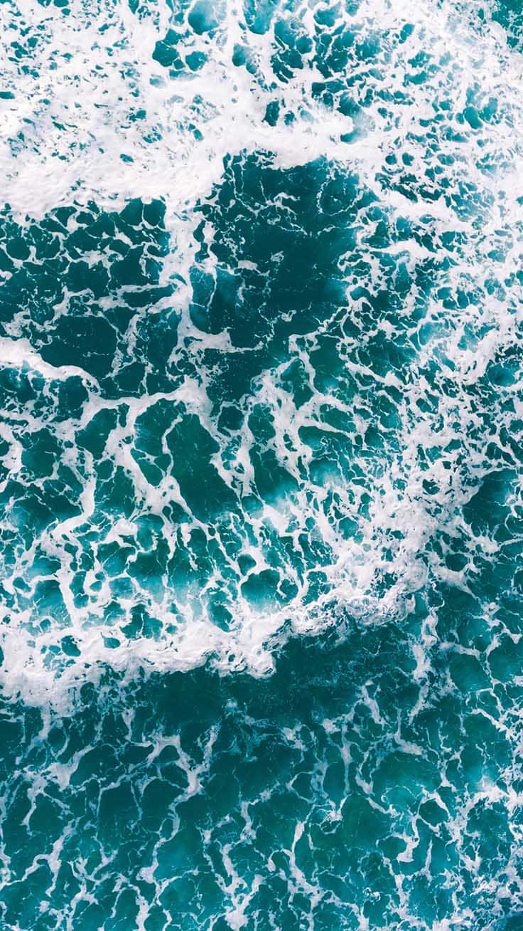 現代風格代表：青綠色 iPhone 壁紙 — 從高空俯瞰，碧綠色的海浪拍打著白色泡沫，形成複雜的圖案。
