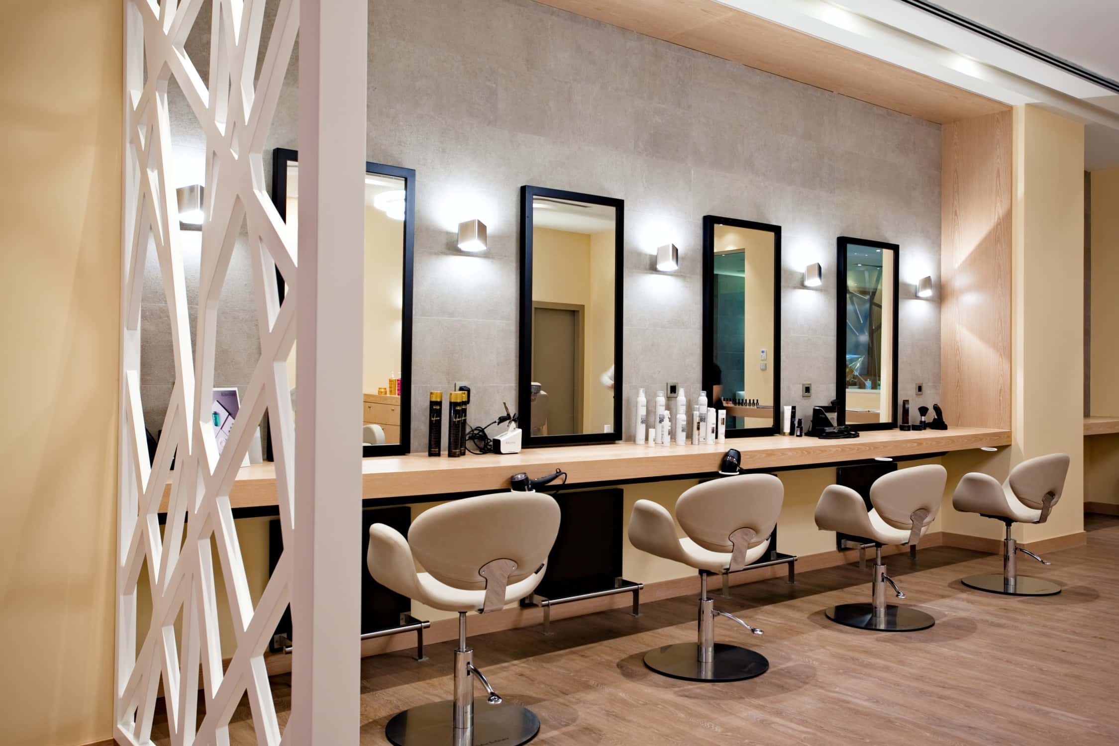 Hair Salon 桌布 壁紙 — 現代髮廊，配有米色椅子、黑色鏡子和木製櫃檯，在溫暖燈光下。