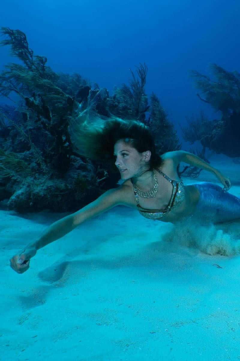 一位女性在藍色海洋中靠近珊瑚和沙灘游泳