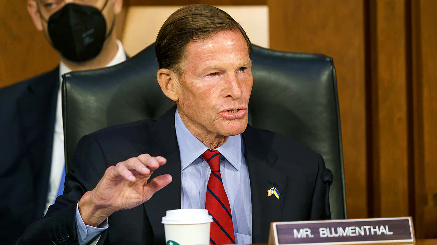 參議員理查德·布盧門撒爾在正式聽證會上發言，桌上放著一杯星巴克。