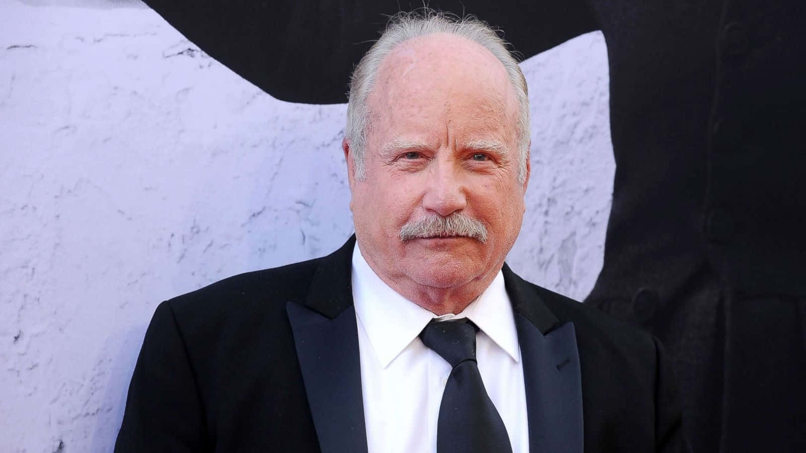 一位穿著黑色燕尾服、留鬍子的男士在正式場合。