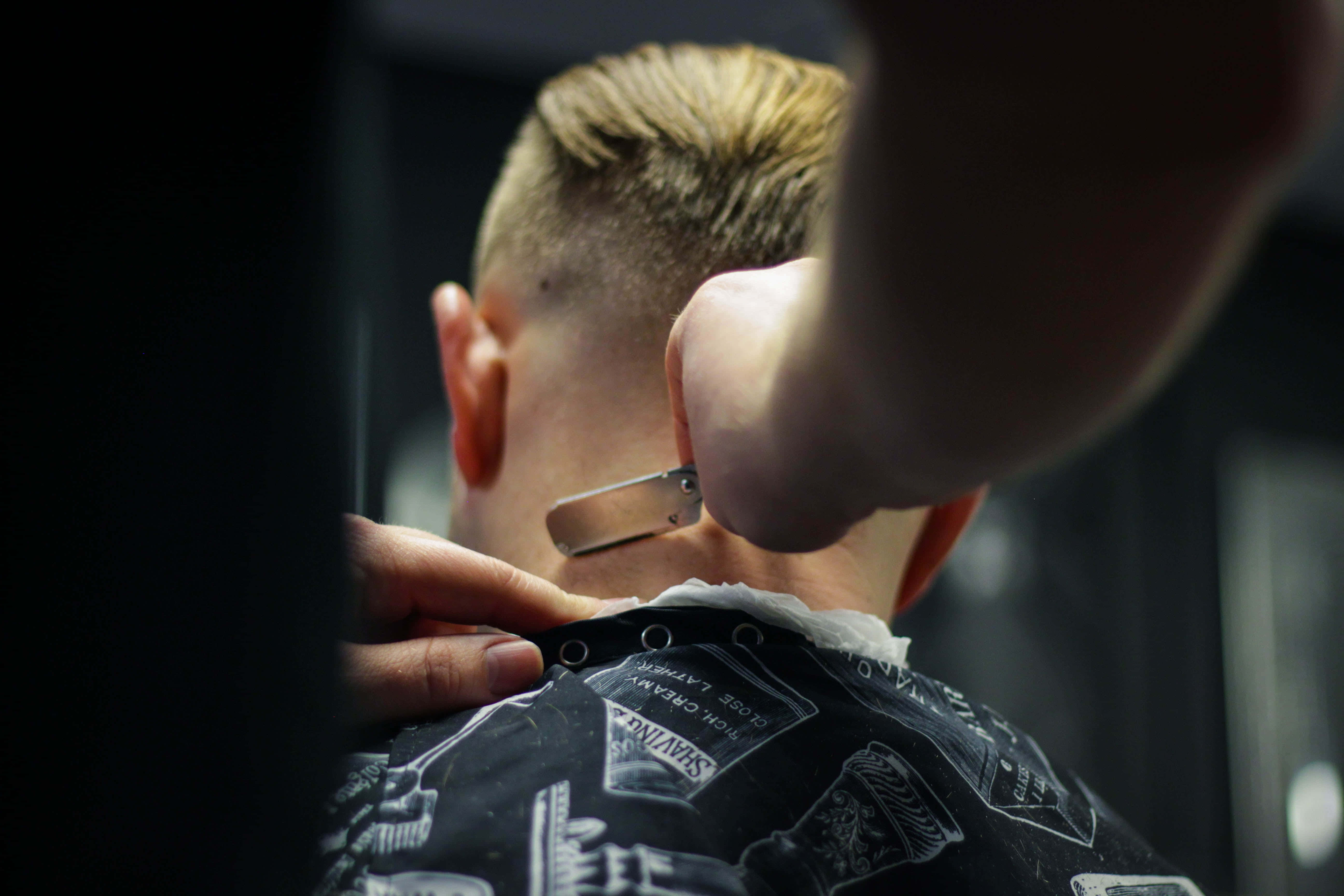 Barber 桌布 壁紙 — 理髮師喺昏暗嘅理髮店用直剃刀修剪男人短金髮嘅特寫。