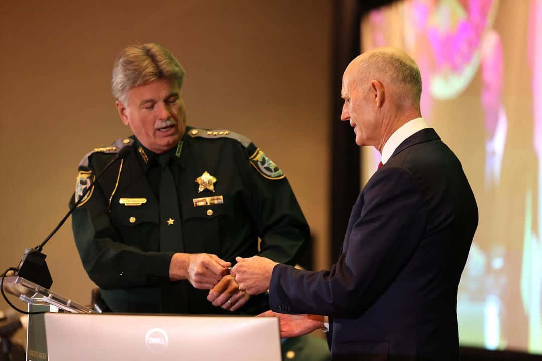 警長在頒獎典禮的講台上與穿西裝的男子握手。