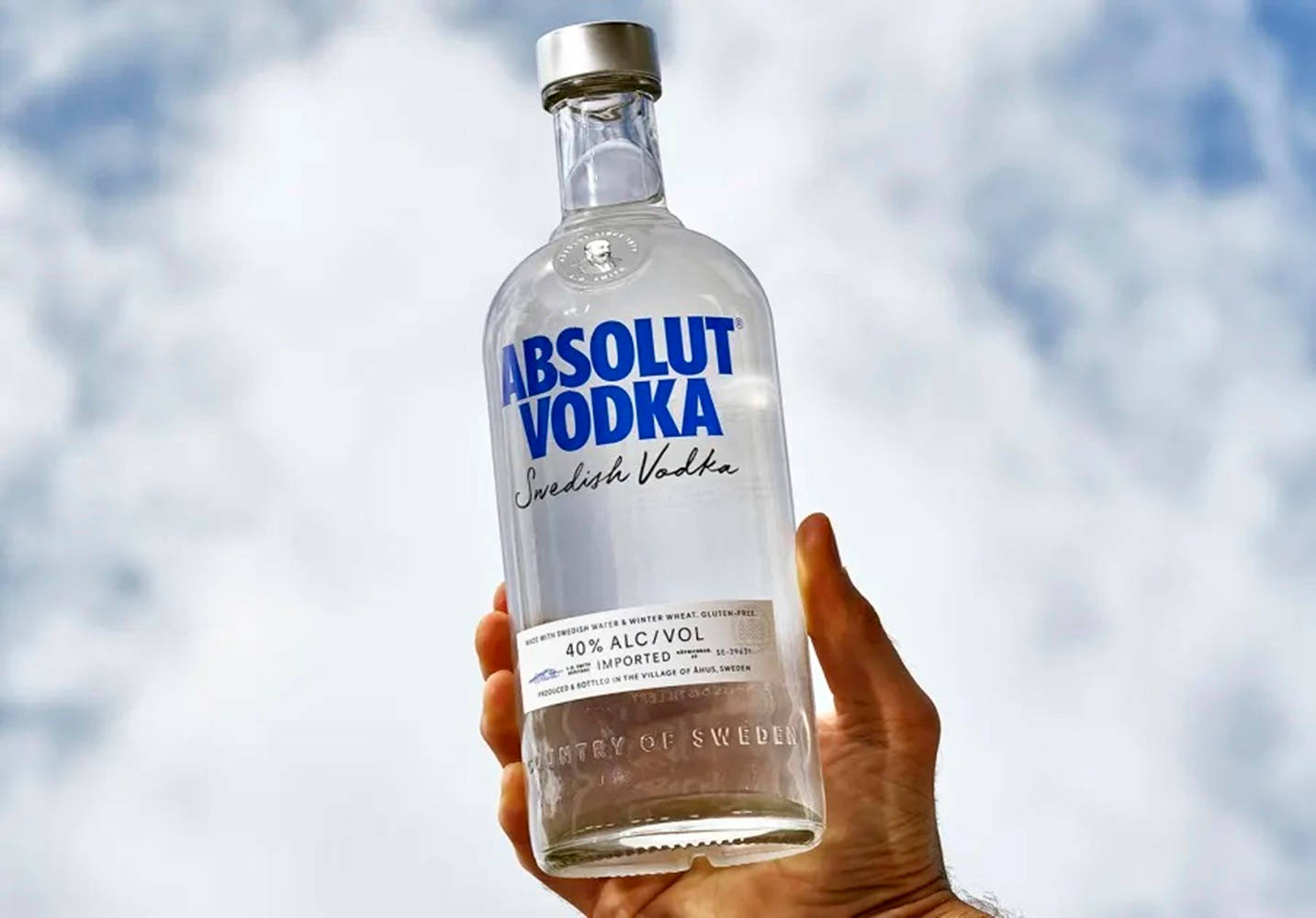 手拿Absolut Vodka酒瓶，背景陰天