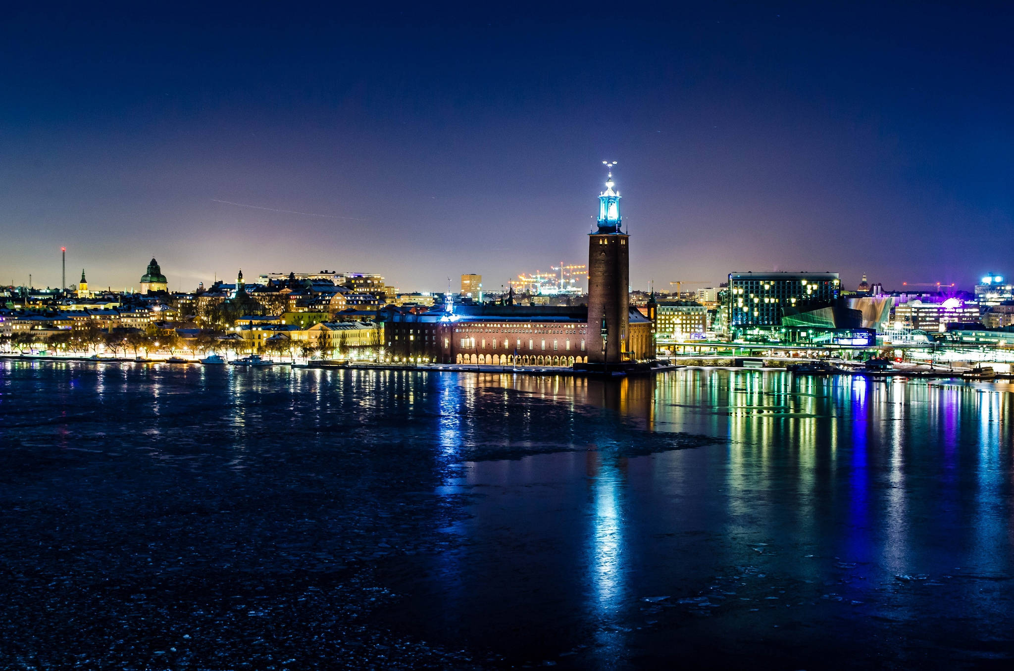 瑞典夜景城市天際線 壁紙 — 斯德哥爾摩令人驚嘆的夜景，標誌性的斯德哥爾摩市政廳亮起燈光，倒映在下方冰冷的河水中。