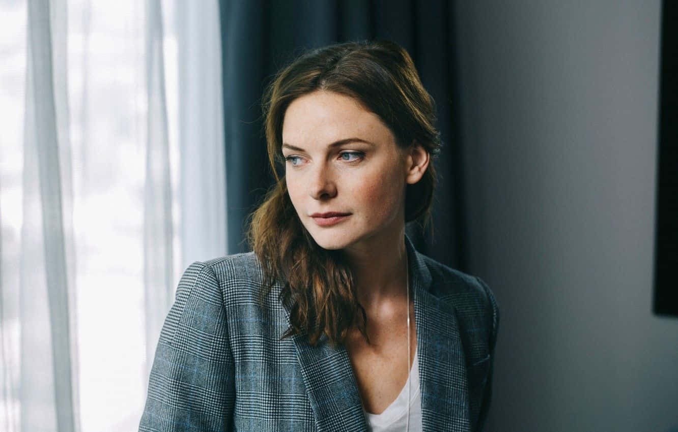 穿著格子西裝外套的女性在窗邊若有所思地凝視