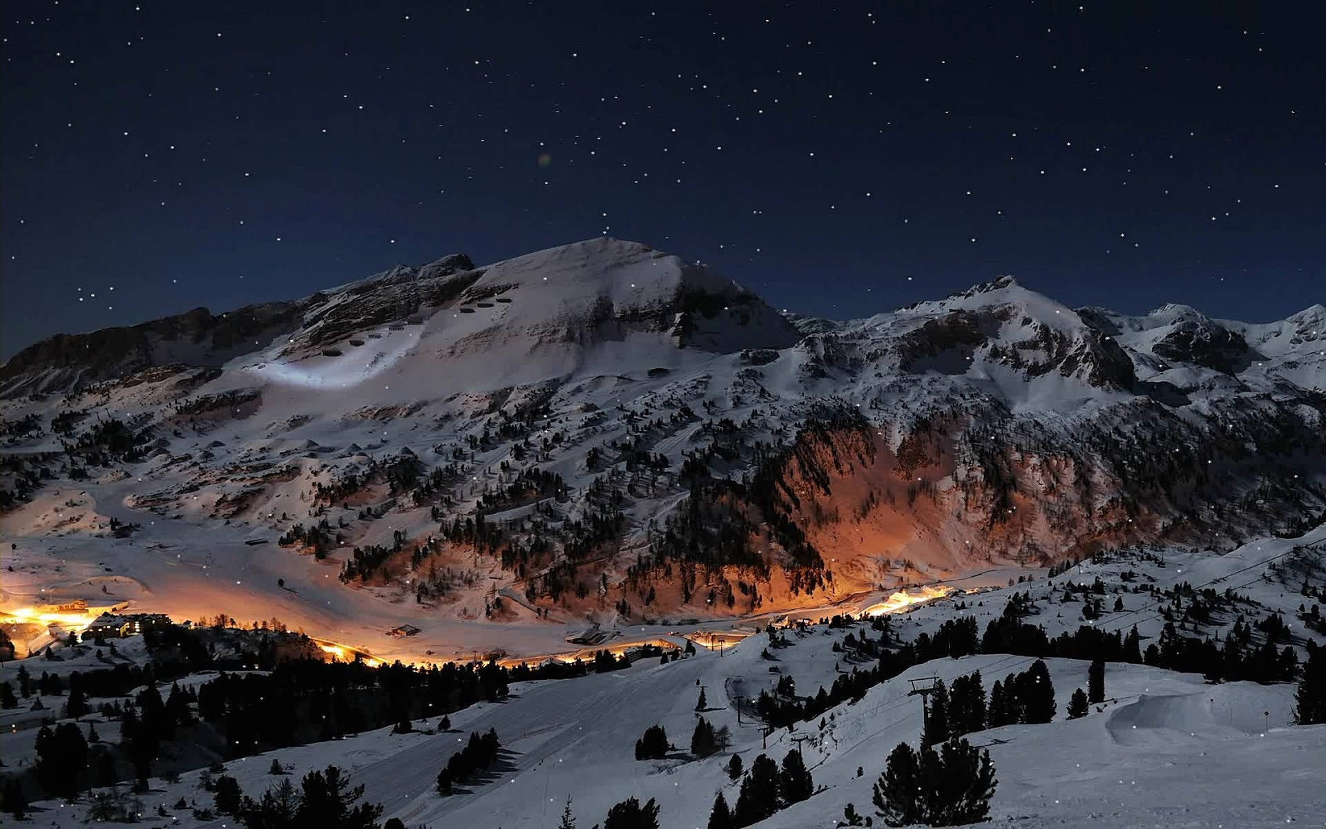 瑞士阿爾卑斯山冬季壯麗全景 壁紙 — 白雪覆蓋的山峰，在繁星點點的夜空下，山谷中溫暖的燈光閃爍。