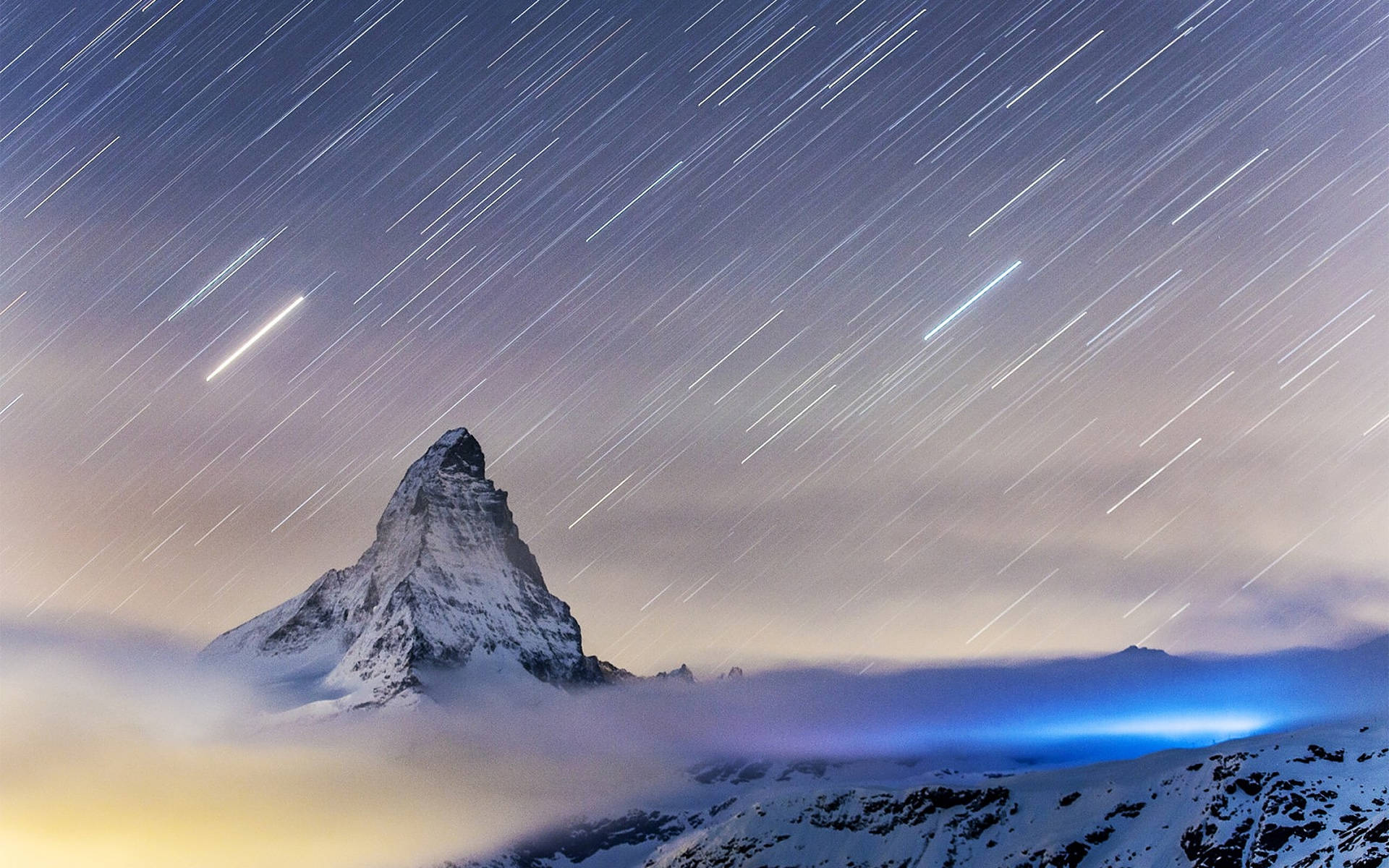 瑞士阿爾卑斯山流星雨 壁紙 — 星軌劃過夜空，位於雲層之上、白雪覆蓋的馬特洪峰山頂。
