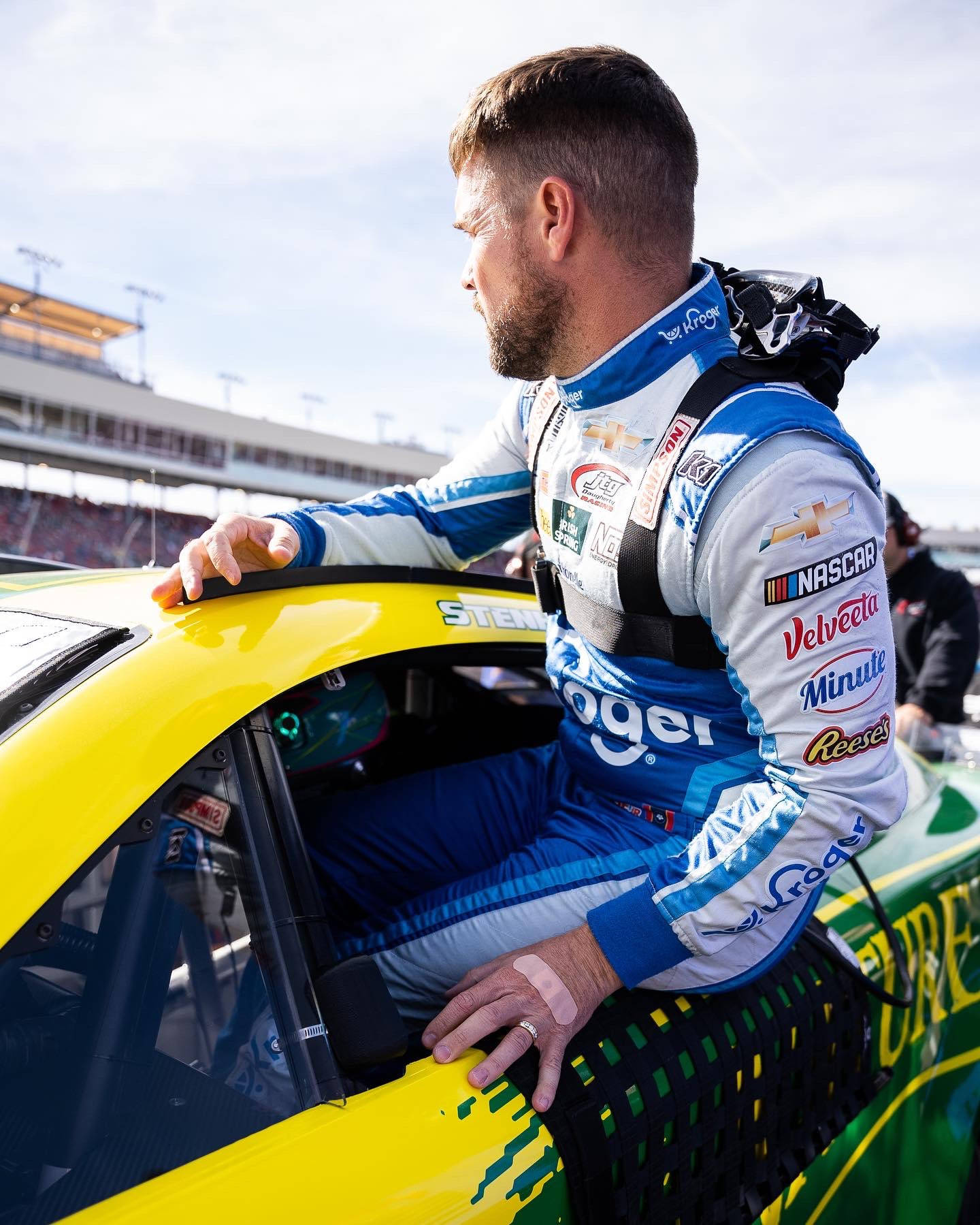 NASCAR車手身穿賽車服從黃色賽車中探出身子在賽道上