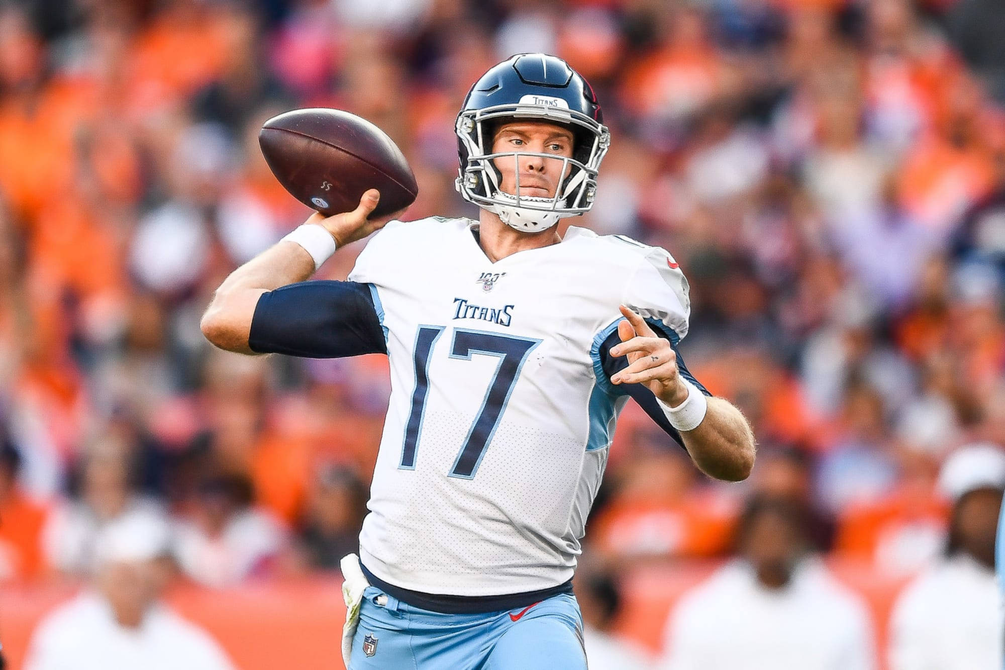 瑞安·坦尼爾田納西泰坦隊NFL比賽 壁紙 — 田納西泰坦隊的四分衛身穿白色17號球衣，在白天比賽中準備投擲橄欖球，背景是模糊的橙色人群。