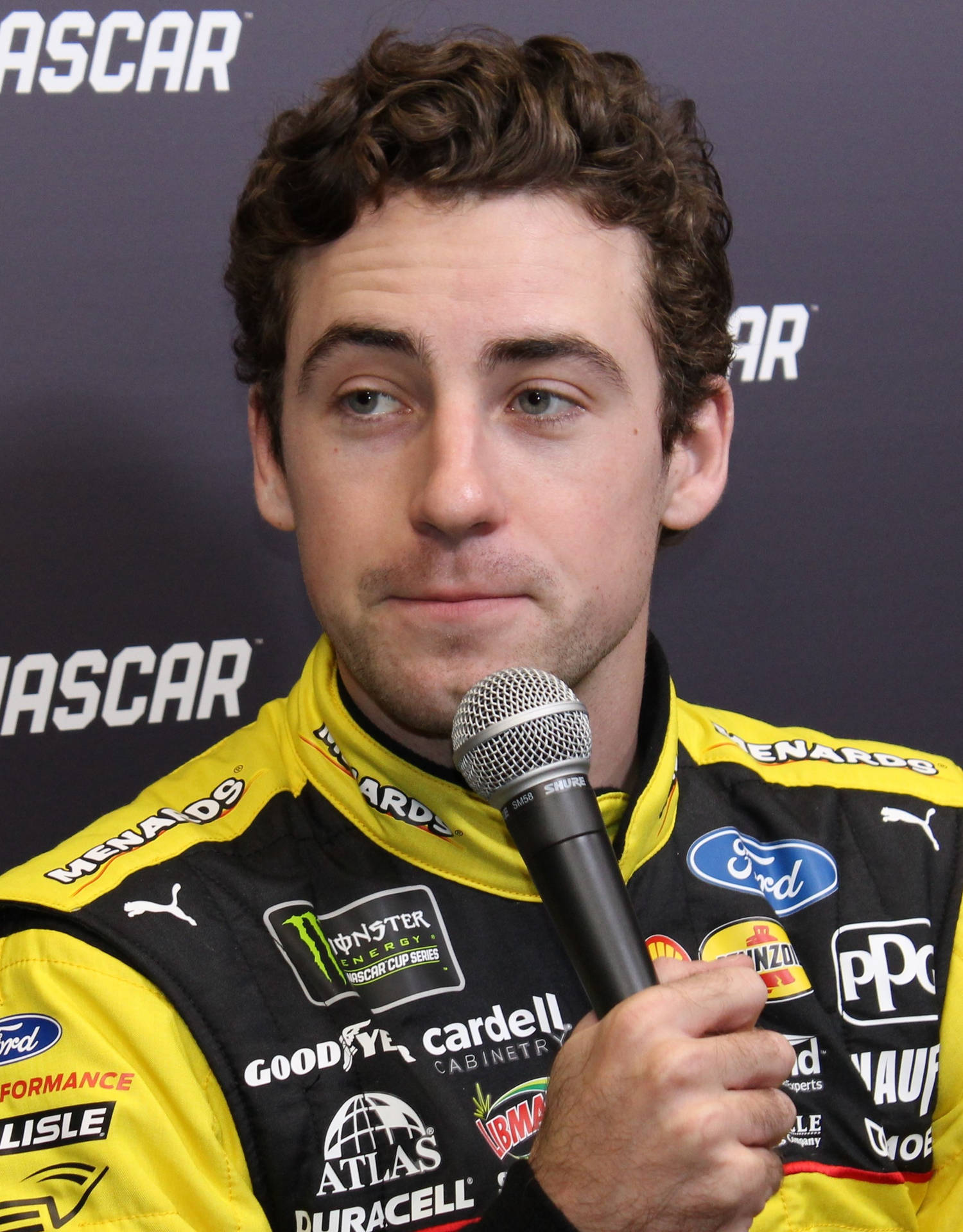 身穿賽車服的NASCAR車手在新聞發布會上拿著麥克風。
