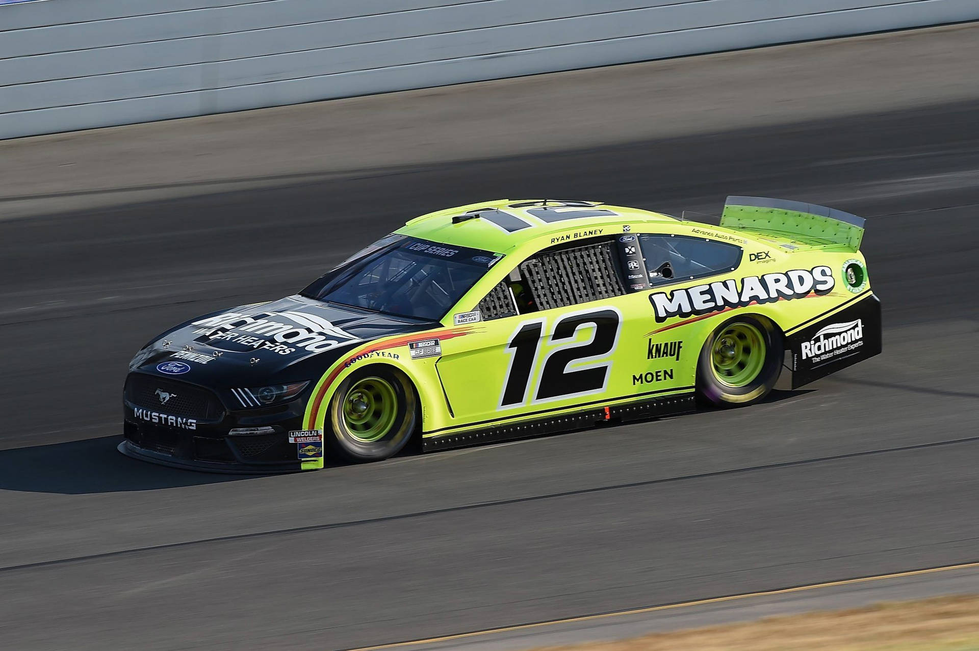 一輛檸檬綠和黑色的NASCAR賽車在賽道上飛馳。