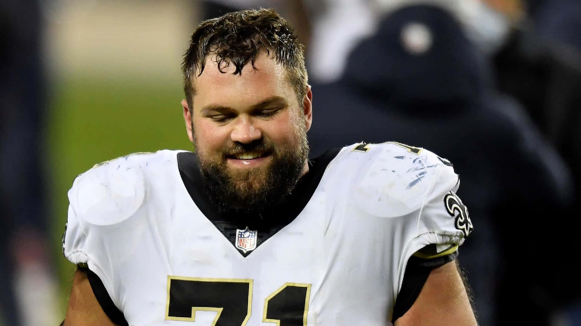 留鬍子的NFL球員在夜晚的足球場上微笑。