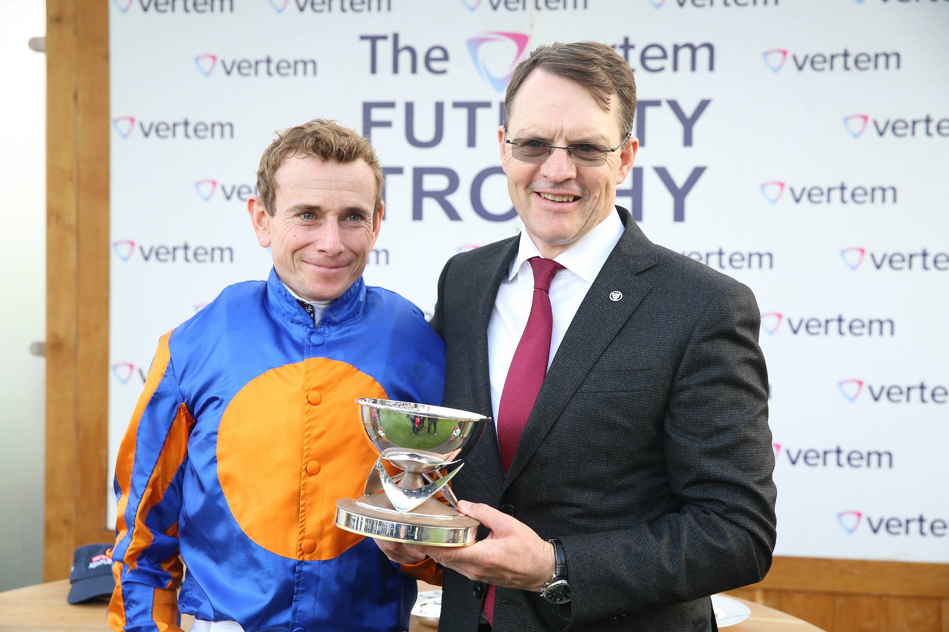騎師和官員在Vertem Futurity Trophy活動中手持獎盃。