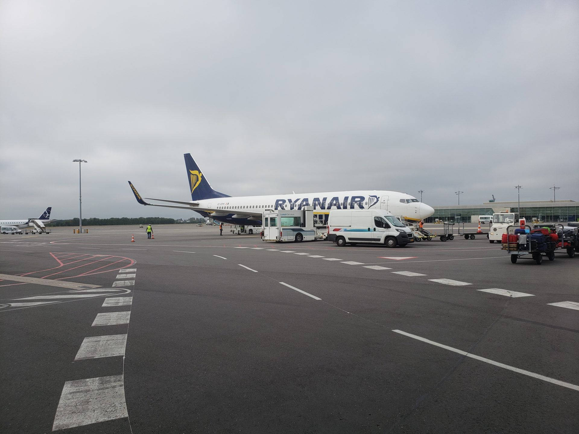 瑞安航空飛機停泊在機場閘口，有地勤人員和服務車輛。