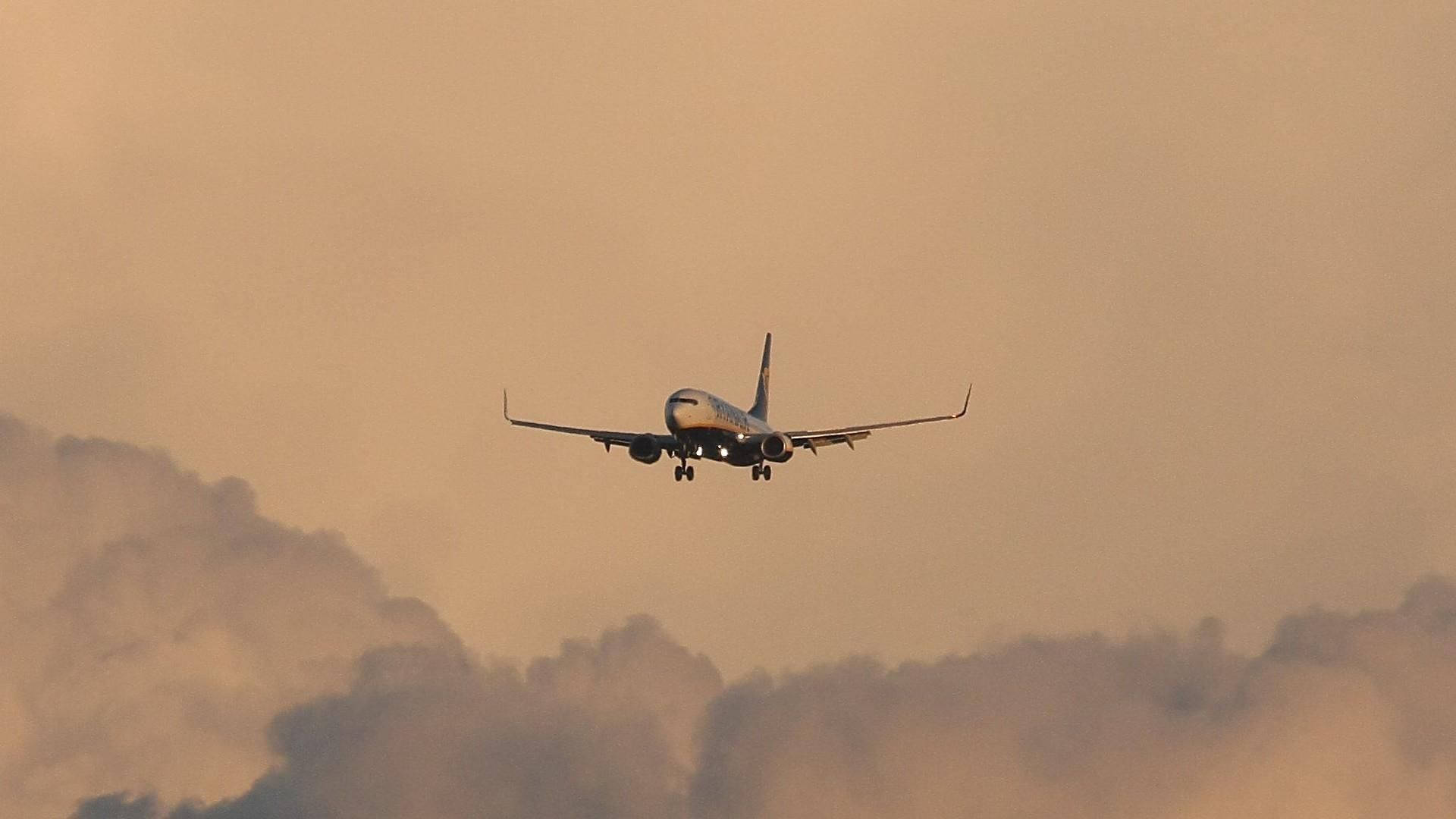 飛機在日落時穿過橙色雲層下降