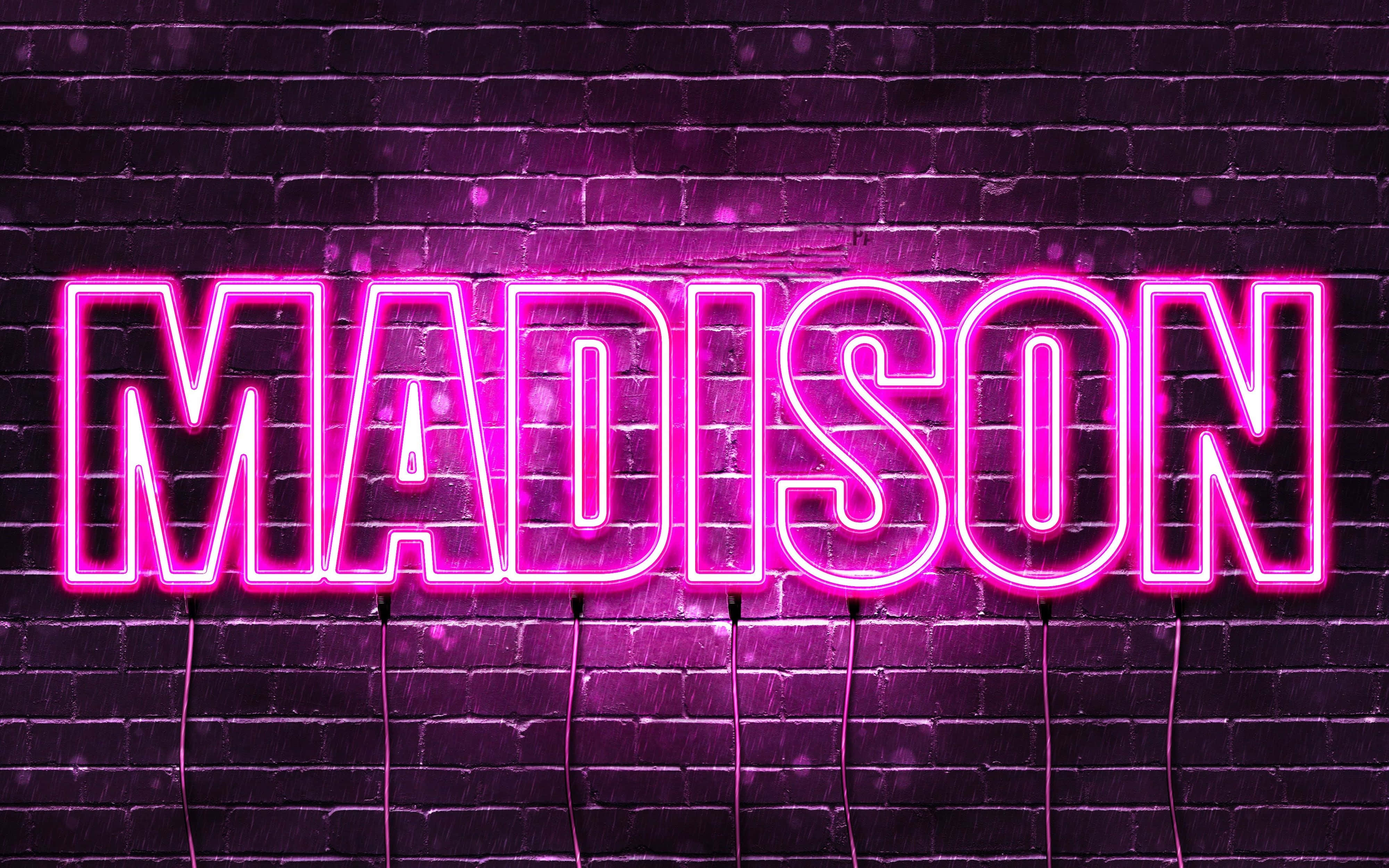 瑪迪遜霓虹字樣 4K 壁紙 — 鮮豔的粉紅色霓虹燈招牌拼寫MADISON，在帶有可見電線的深色紋理磚牆上發光。