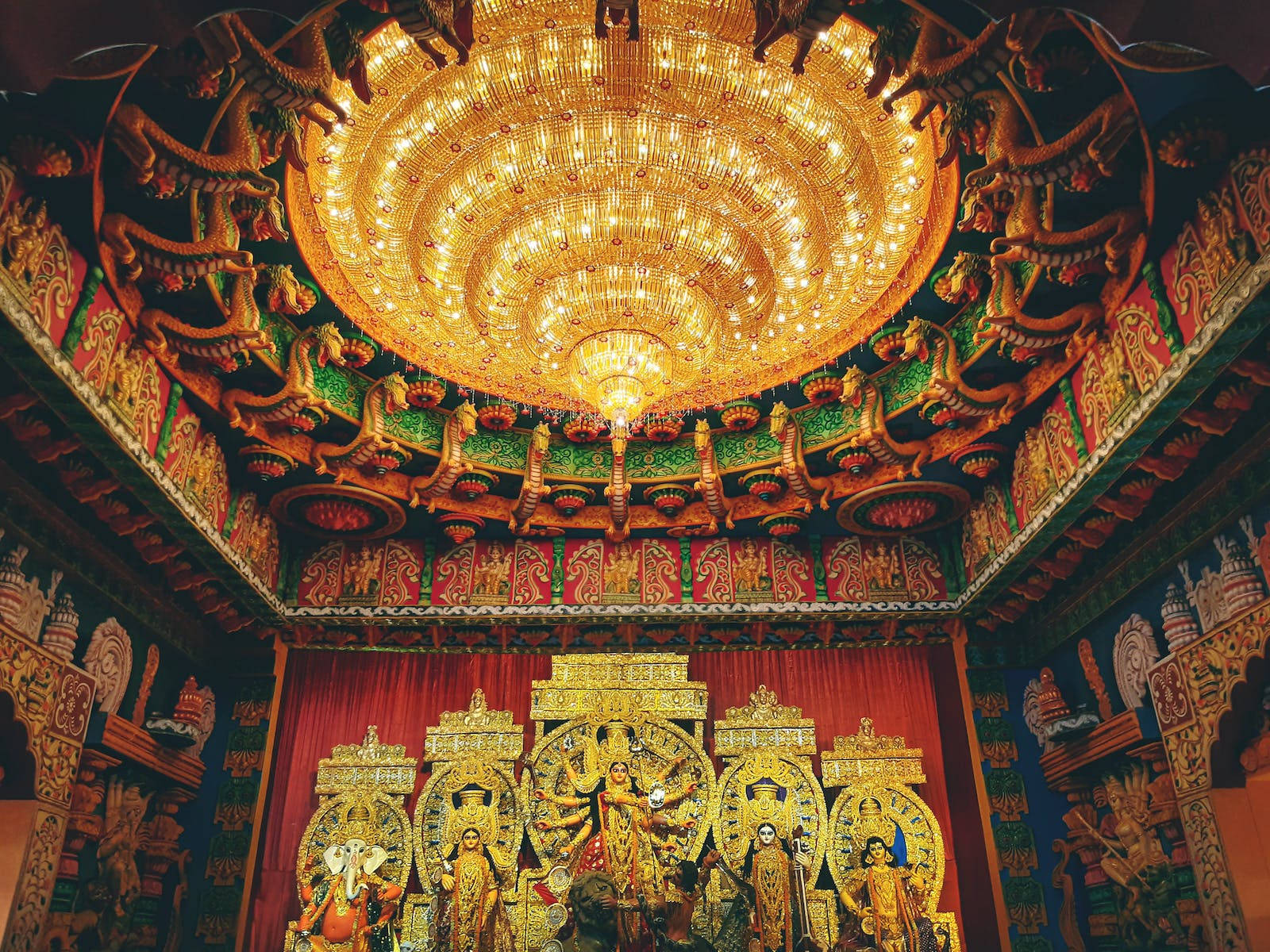 裝飾華麗的寺廟內，金色印度教神像與大型吊燈。