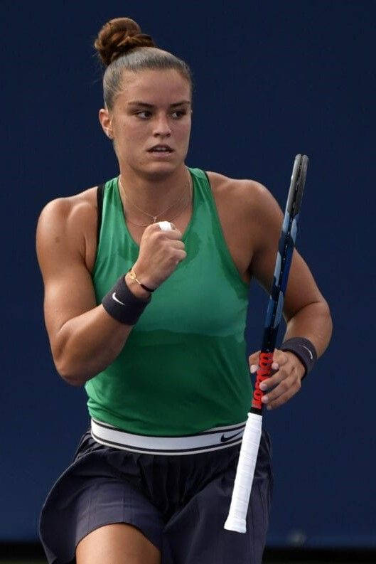身穿綠色上衣和深藍色短褲的女網球運動員在比賽中握拳。