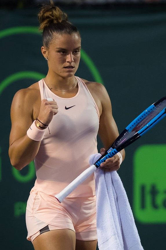 女網球選手握緊拳頭拿著球拍和毛巾慶祝勝利。
