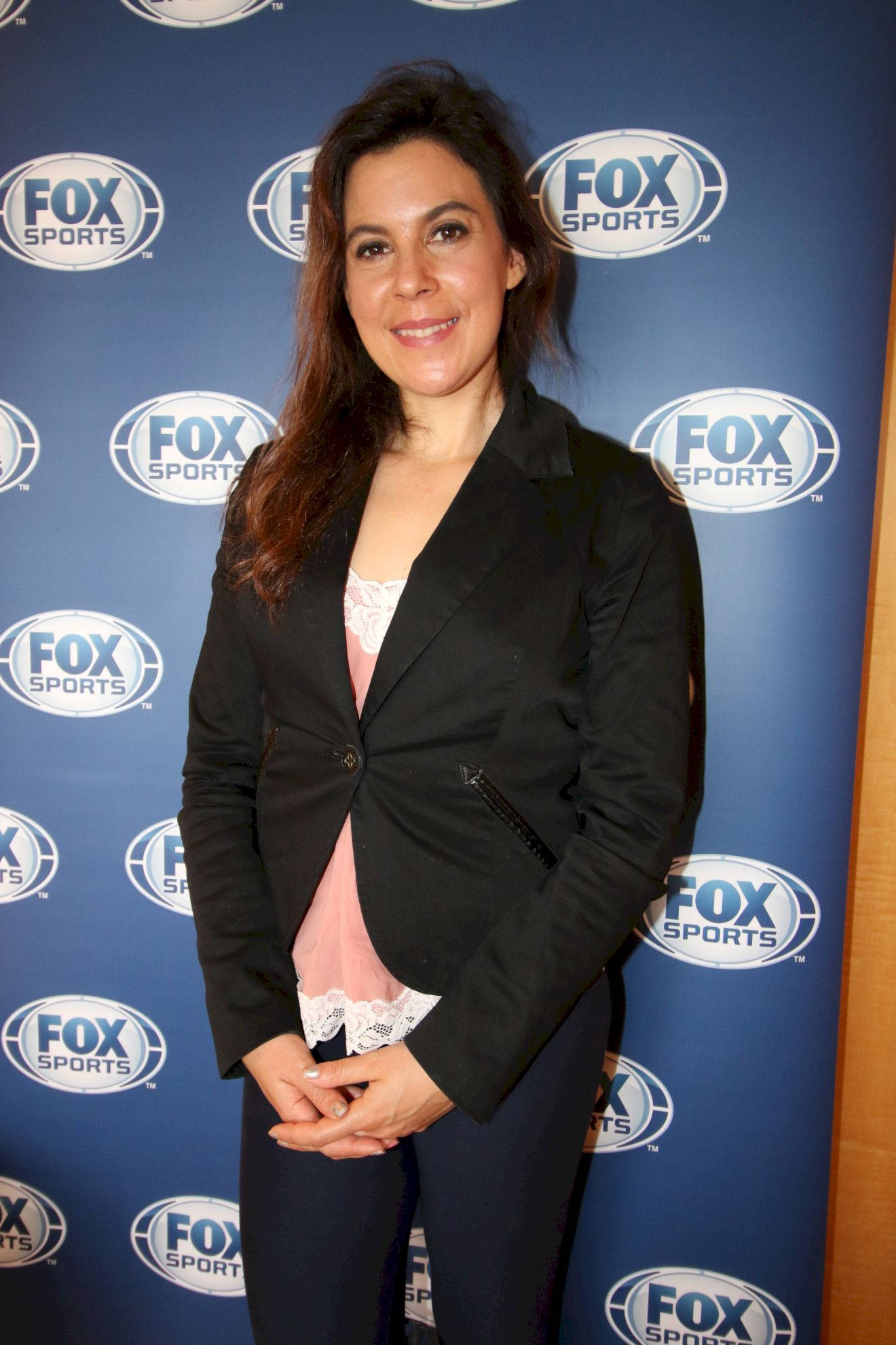 瑪麗昂·巴托利在Fox Sports背景前拍照 壁紙 — 一位身穿黑色西裝外套、面帶微笑的女性自信地站在藍色Fox Sports品牌背景前。