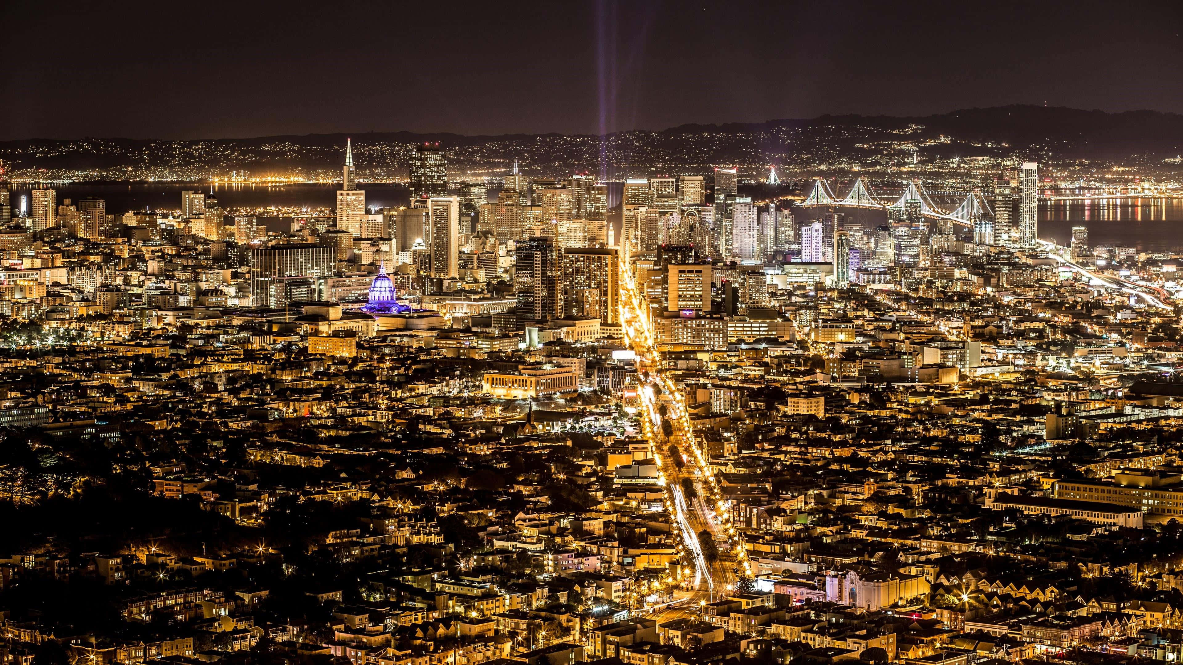 璀璨夜景城市——最佳舊金山背景 壁紙 — 三藩市閃爍天際線的夜間空中景觀，金門大橋和城市燈光延伸至山丘。