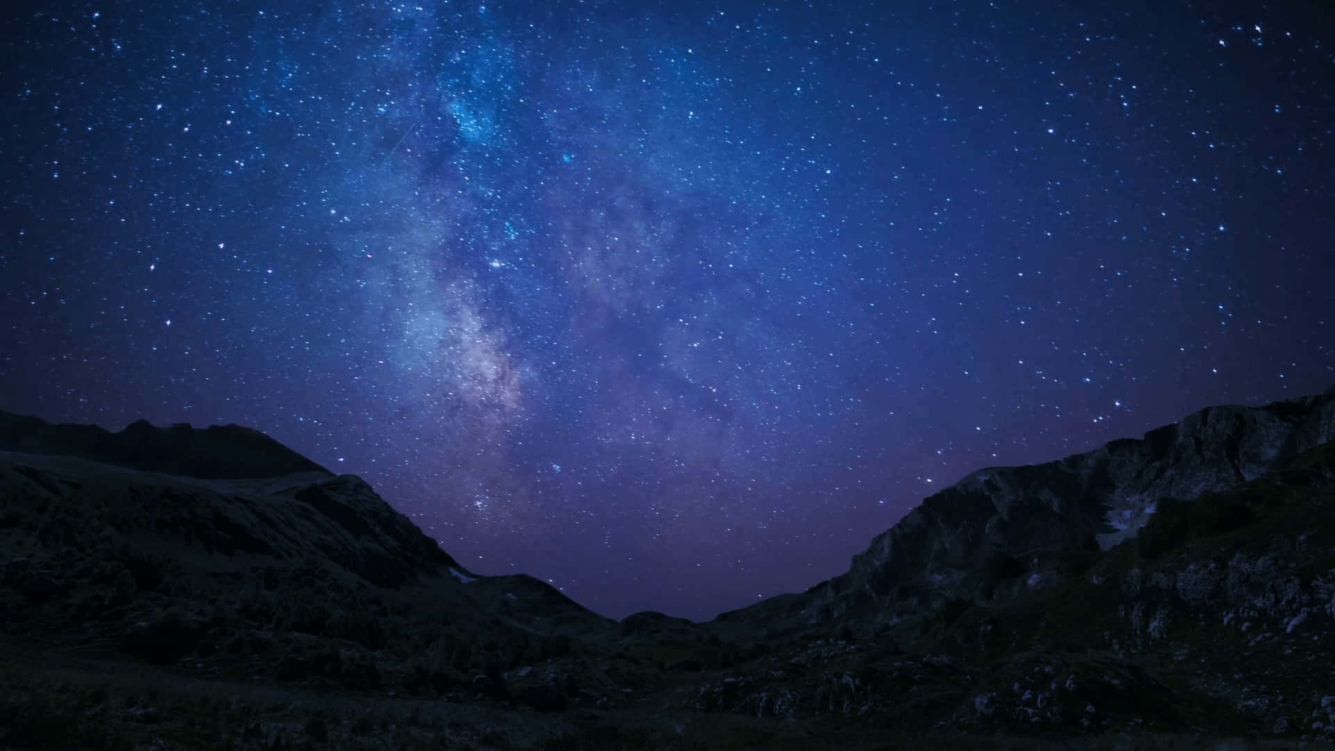 黑暗的山脈襯托著充滿活力的星空，銀河在上方閃耀。