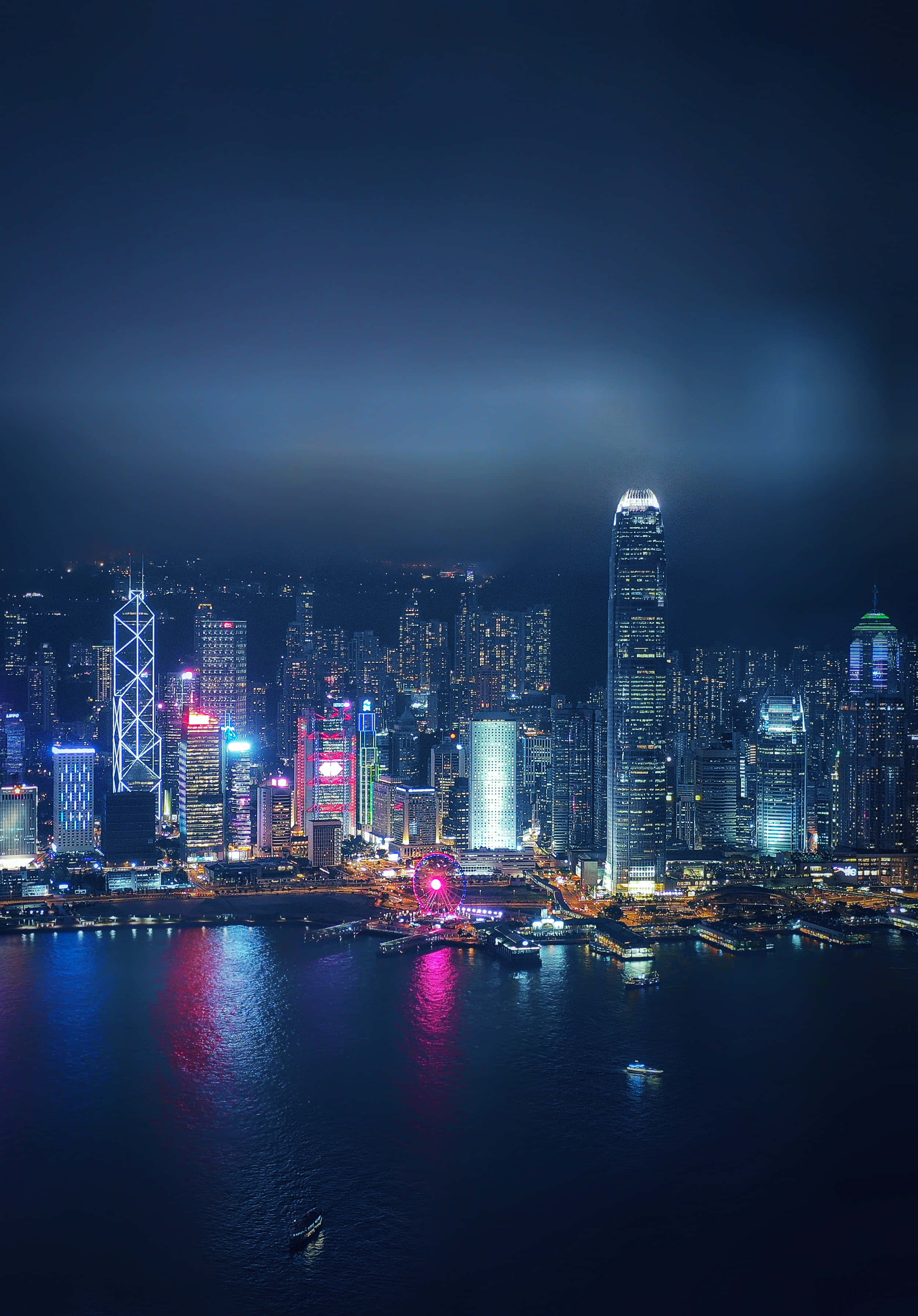 璀璨奪目的夜間城市景觀 壁紙 — 香港令人目眩的夜景，摩天大樓在漆黑的天空下閃耀，燈光倒映在下方水面。