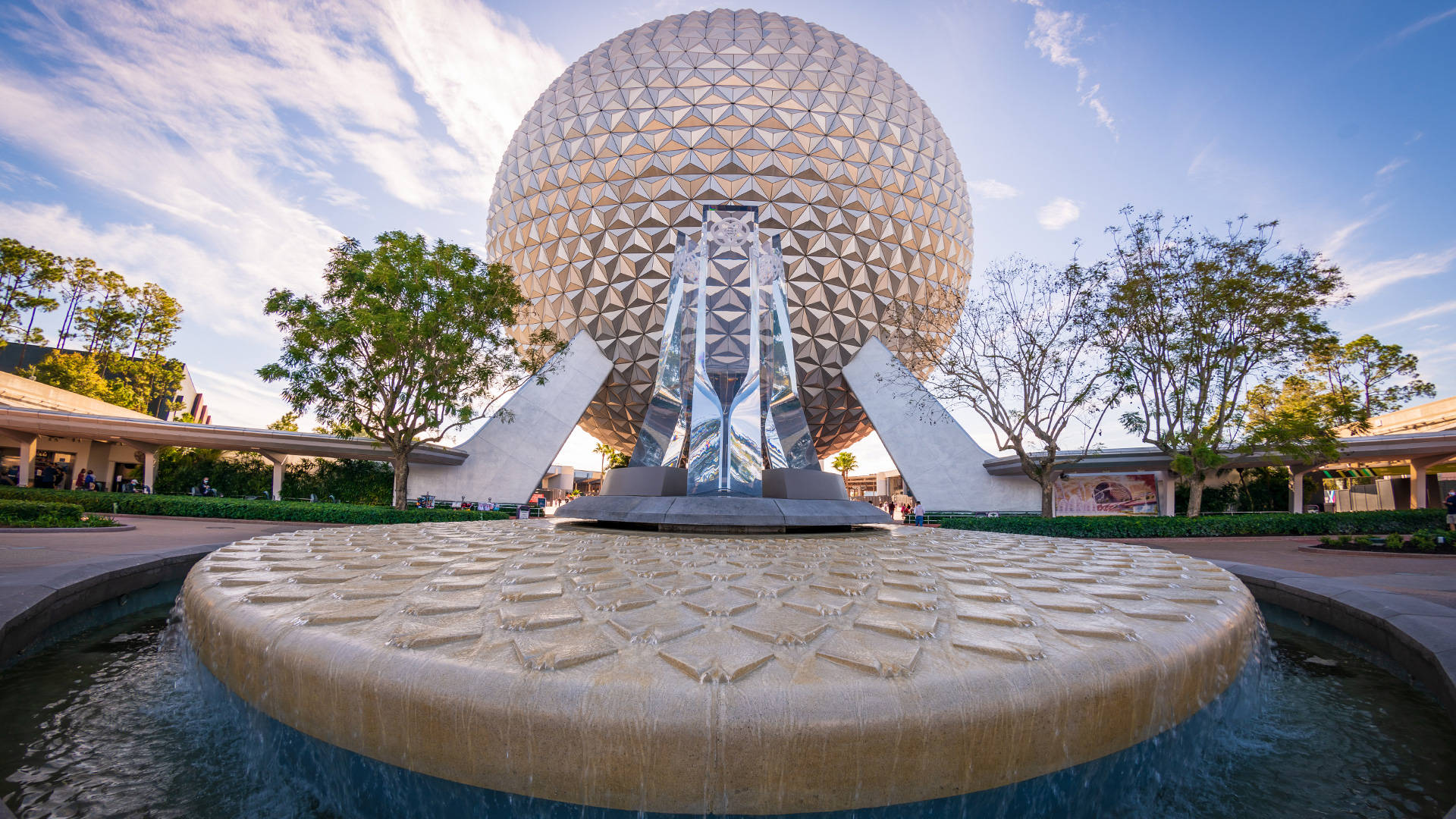 環球影城 Epcot 球體與噴泉 壁紙 — 一個巨大的測地線球體聳立在一個圓形噴泉上，噴泉有層疊的水流，背景是明亮的藍天和散落的雲朵。