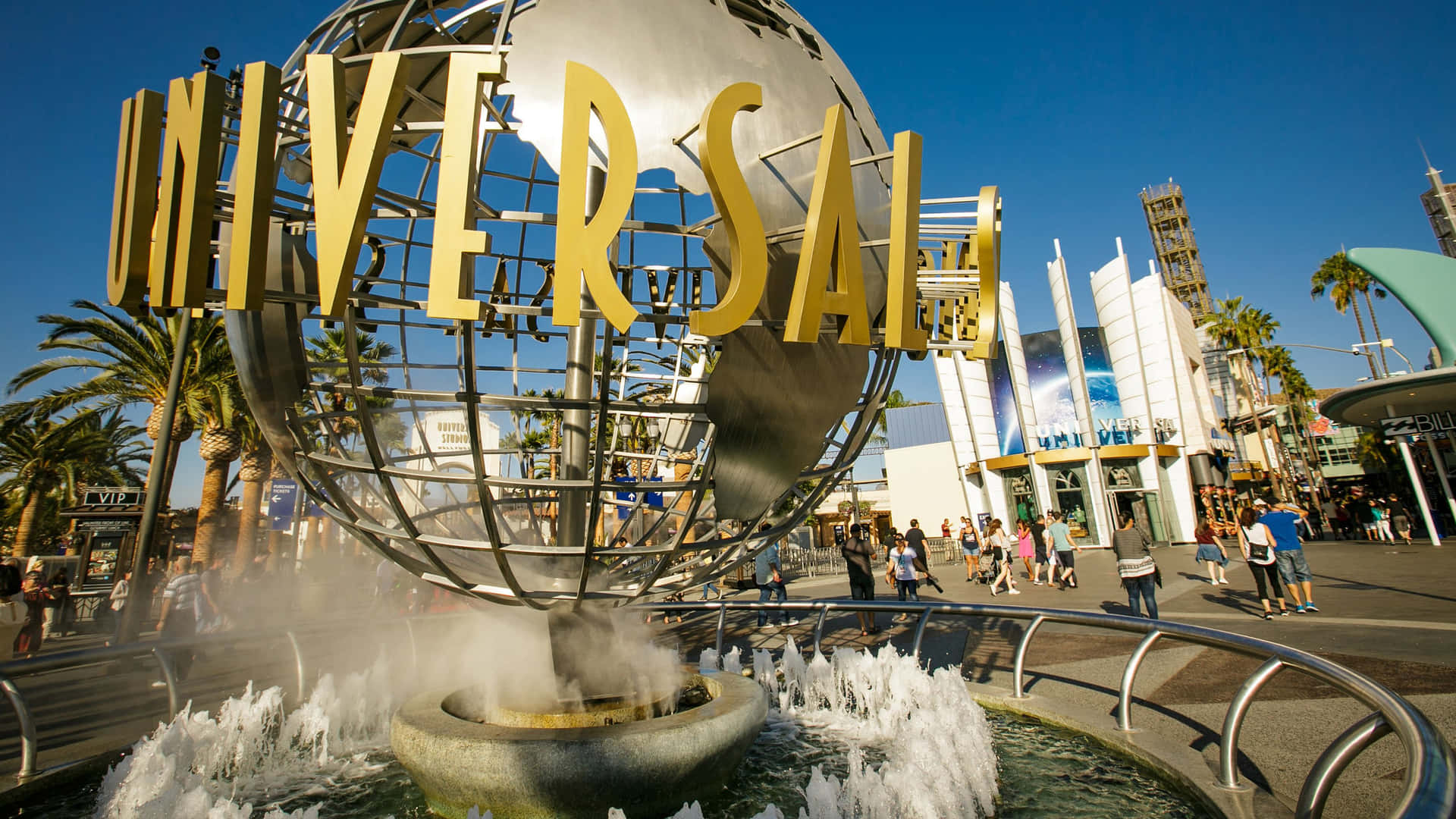 Universal Studios 地球儀噴泉，藍天白雲下，棕櫚樹和遊客環繞。