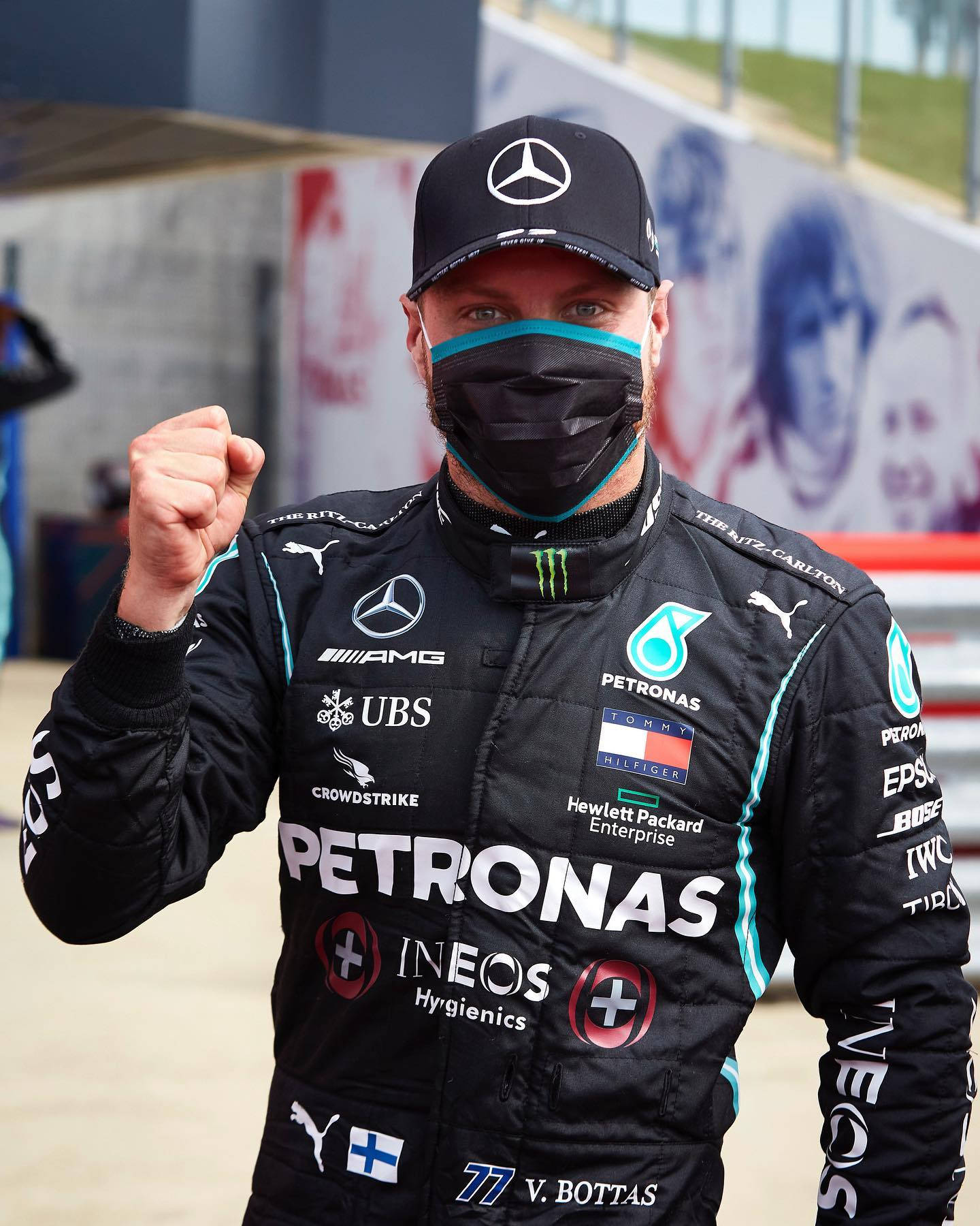 F1車手Valtteri Bottas身穿賽車服和口罩在賽道上慶祝勝利。