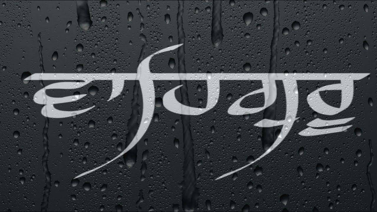 黑暗潮濕表面上的銀色天城文字，帶有雨滴。