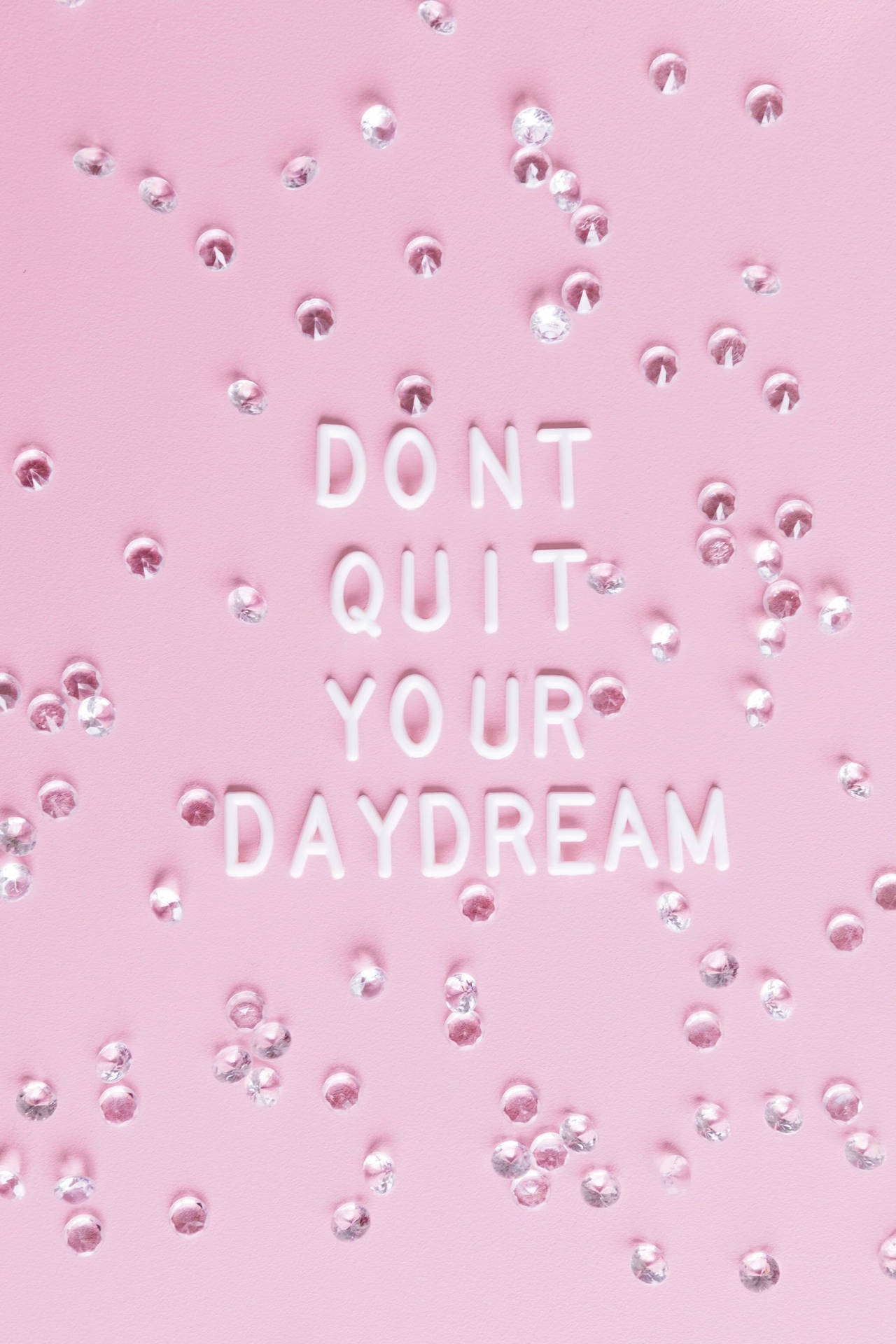 粉紅色背景，白色3D文字寫著「DON'T QUIT YOUR DAYDREAM」，周圍環繞著銀色水鑽。