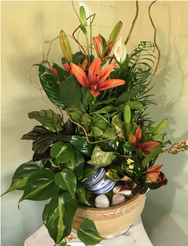 生動室內植物佈置 壁紙 — 一個編織籃子裡盛載著茂盛的花卉佈置，以淡色牆壁為背景，展現鮮豔的橙色百合和綠色葉子。