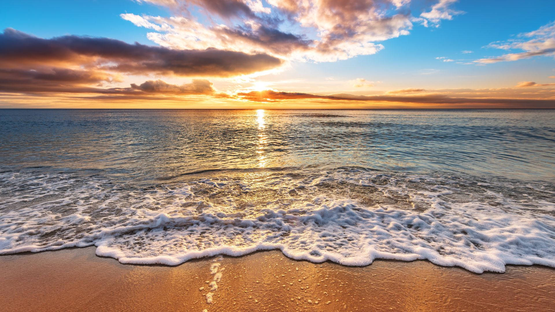 夕陽海浪湧上沙灘，天空色彩繽紛