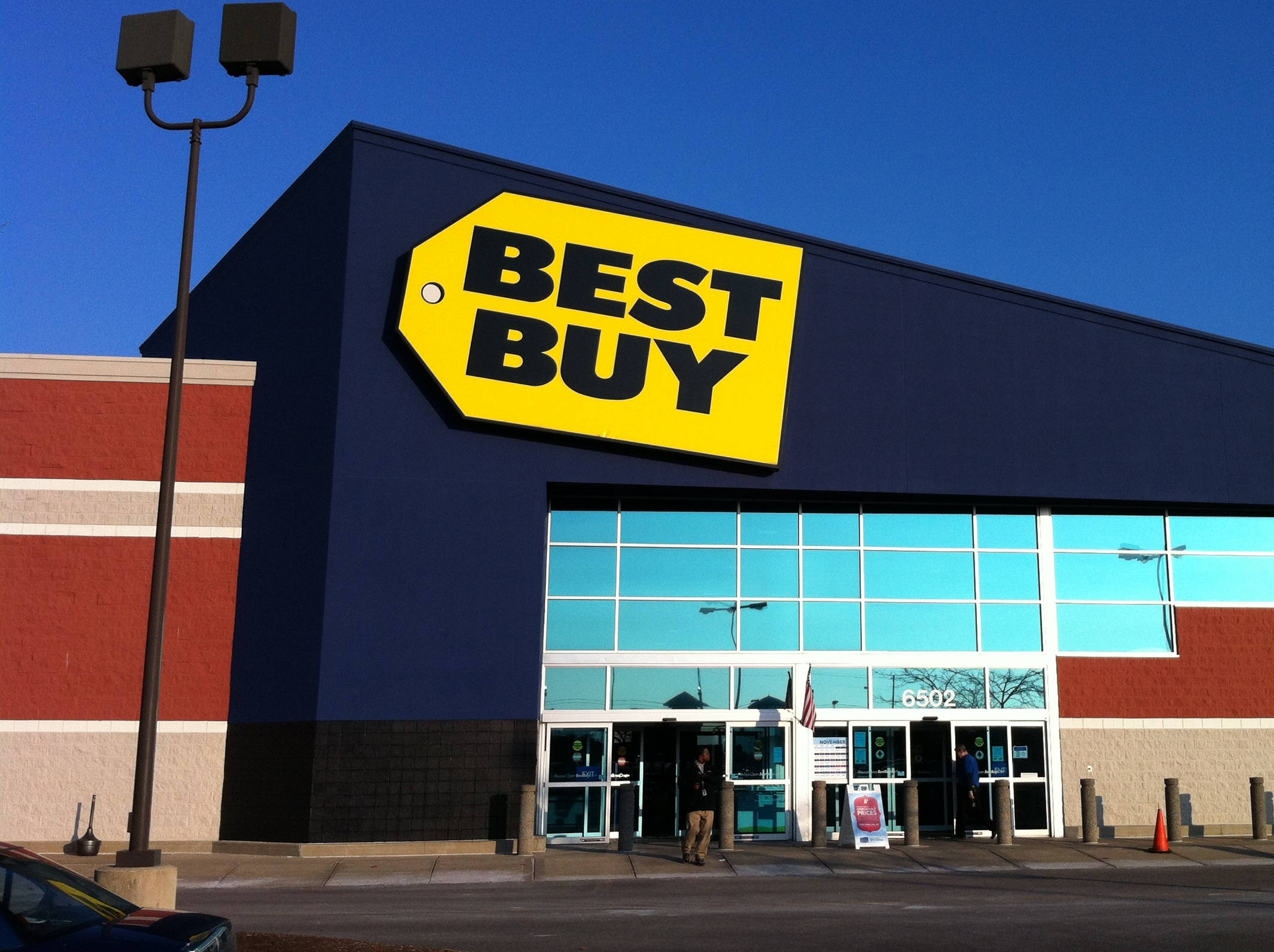 生動的Best Buy建築 壁紙 — 晴朗藍天下，一間亮藍色的Best Buy商店，帶有大型黃色標籤標誌。