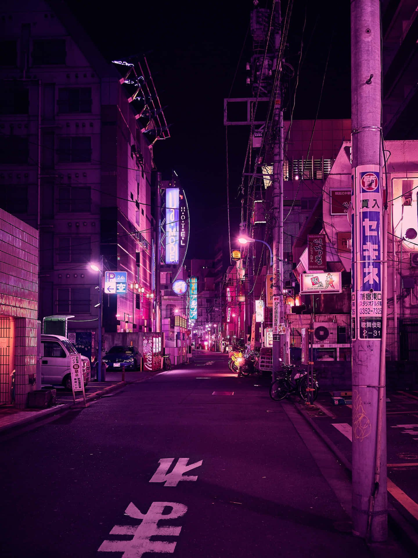 夜晚狹窄的東京街道，被紫色和粉紅色的霓虹燈招牌及路燈照亮。