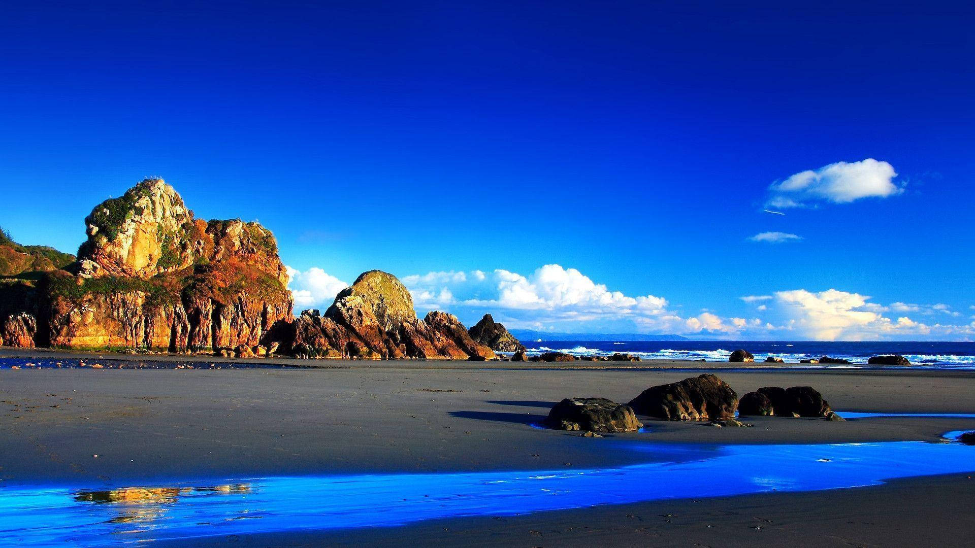 生動風景 Windows Vista 壁紙 — 一個充滿活力的海岸場景，高聳的岩石懸崖在深藍色的天空下，點綴著蓬鬆的白雲。