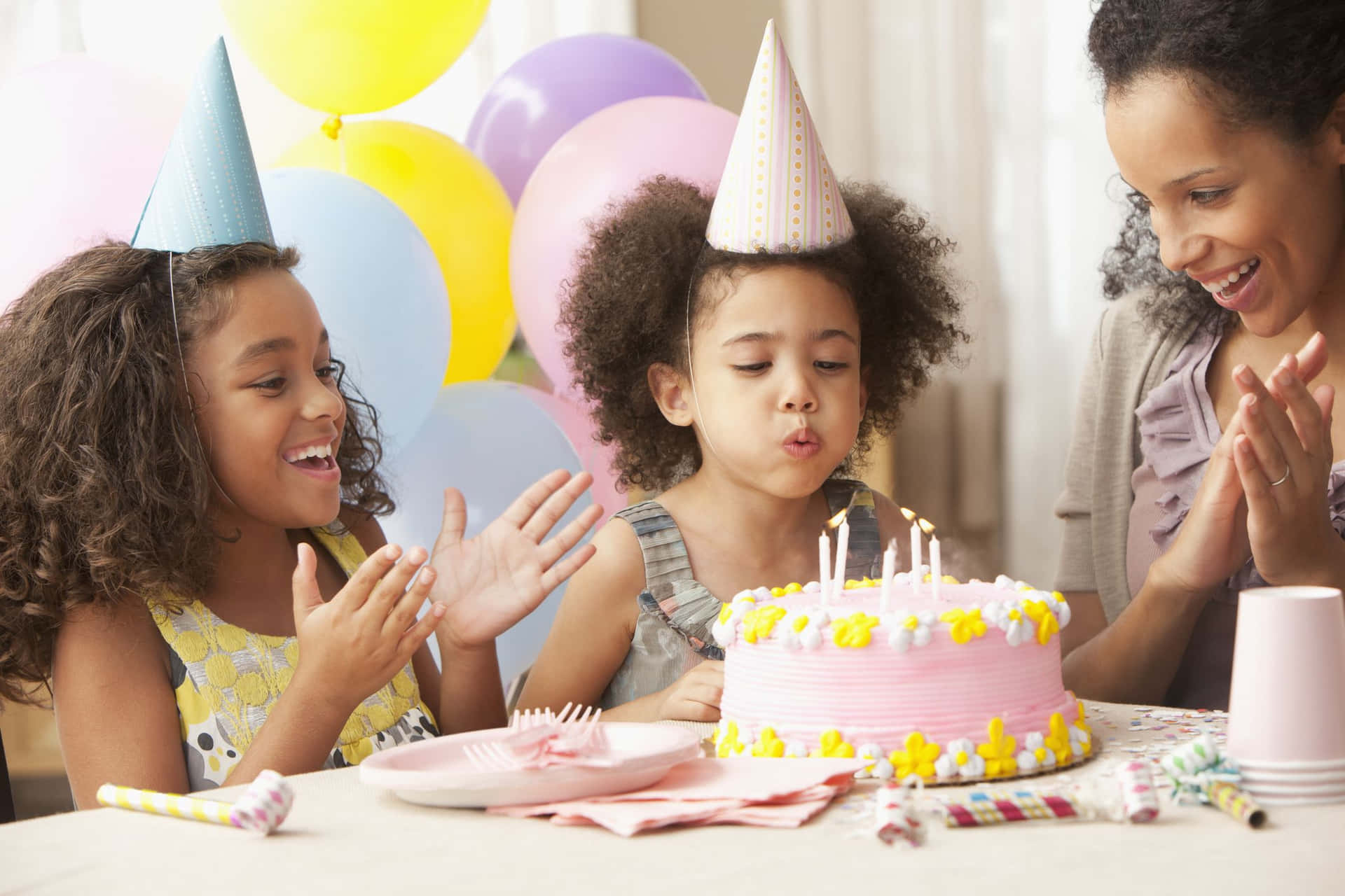 孩子們吹熄生日蠟燭，大人在附近拍手。