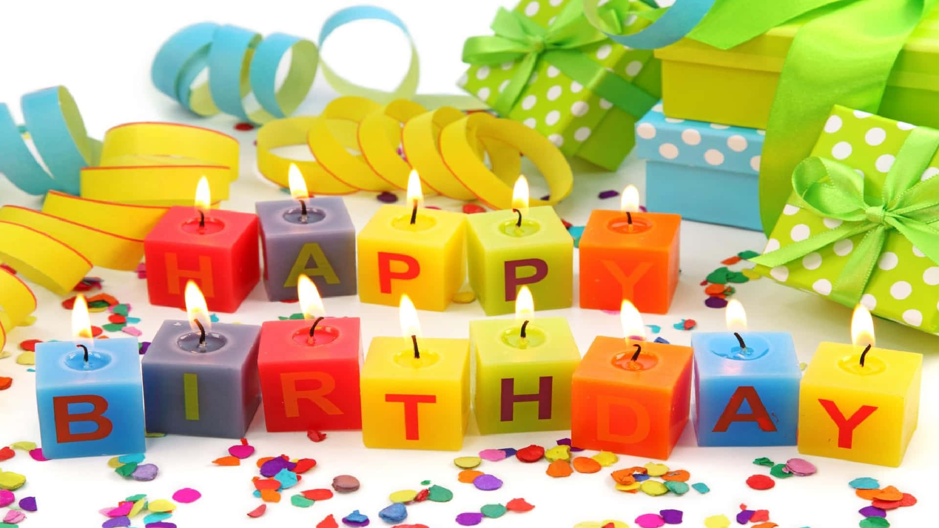 「生日快樂 — 讓今天特別！」 壁紙 — 色彩繽紛的立方體蠟燭拼出 happy birthday，在五彩紙屑和包裝好的禮物中溫暖地發光。