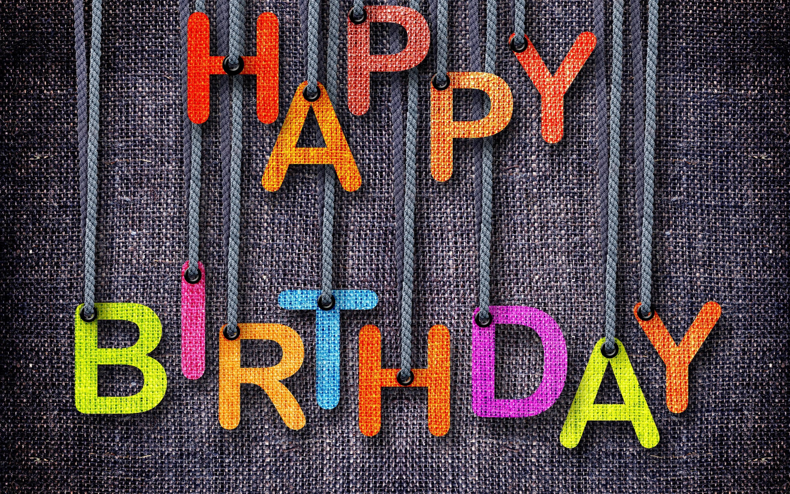 生日快樂繩編字母 壁紙 — 色彩繽紛的布料字母拼出「HAPPY BIRTHDAY」，掛在繩子上，背景為深色紋理。