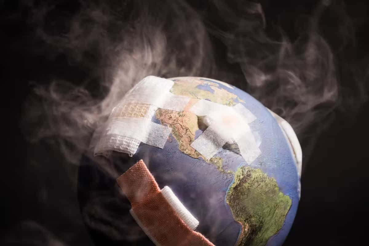 生病的地球氣候變遷圖像 壁紙 — 一個被醫療繃帶覆蓋並在黑暗背景下冒煙的地球儀。