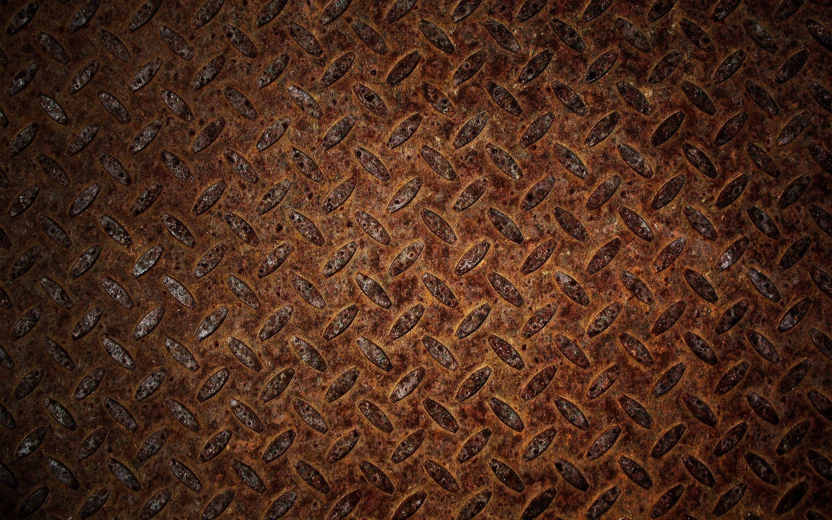 Rust 桌布 壁紙 — 生鏽菱形花紋金屬板的特寫，帶有紋理凹槽和風化的棕色銅綠。